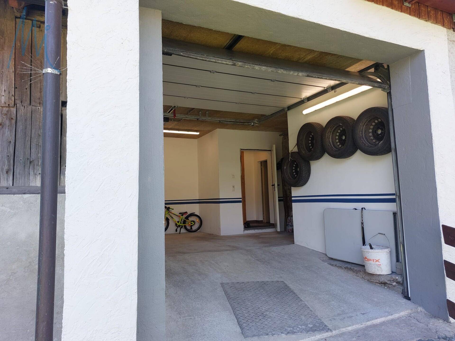 Einfahrt zur Garage mit Rolltor und Platz für Fahrzeuge.