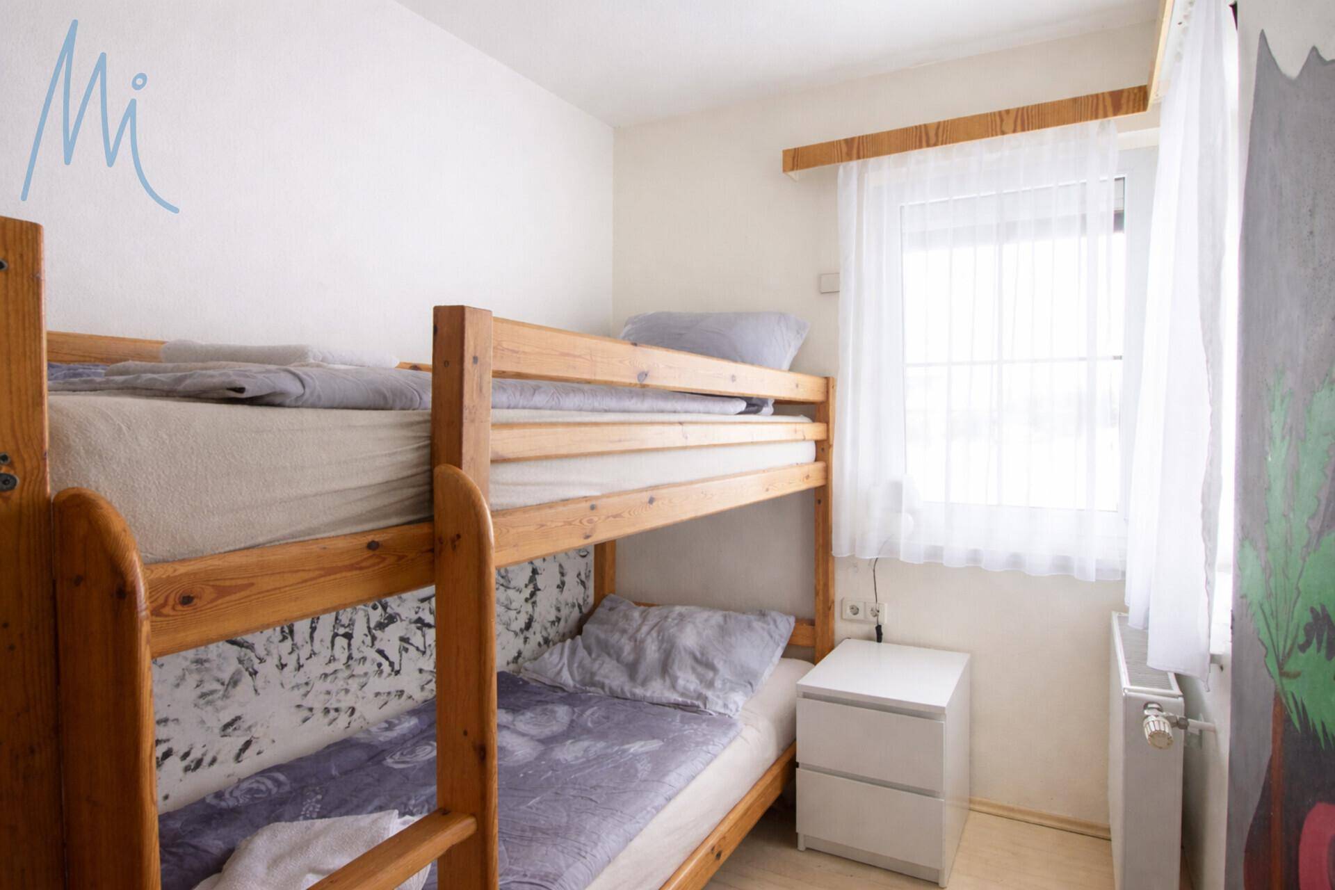 Kinderzimmer mit Etagenbett aus Holz und hellem Fenster, ideal für Gäste.