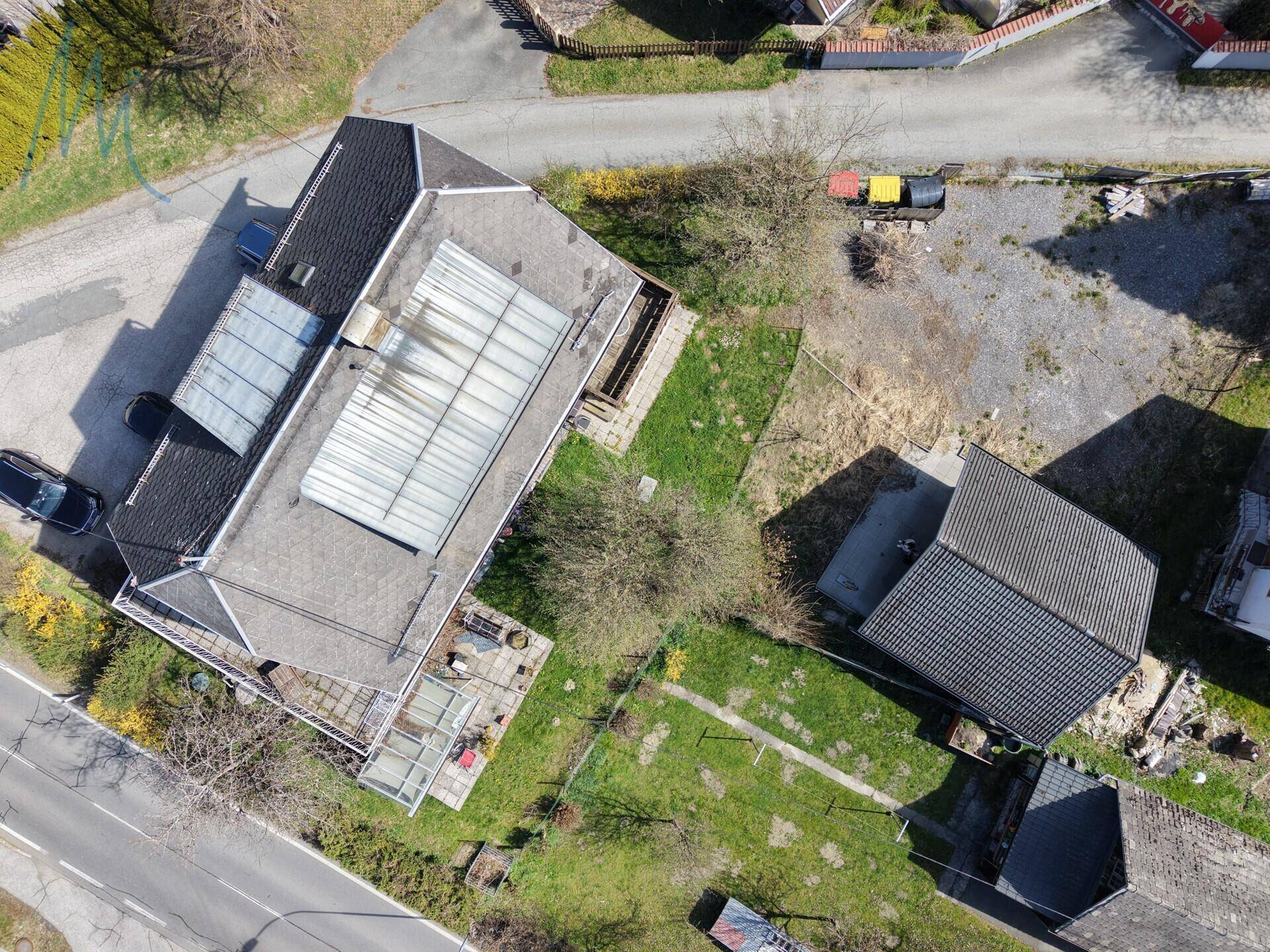 Weitläufige Luftaufnahme des Anwesens mit Haupthaus, Nebengebäude und umliegenden Grünflächen.