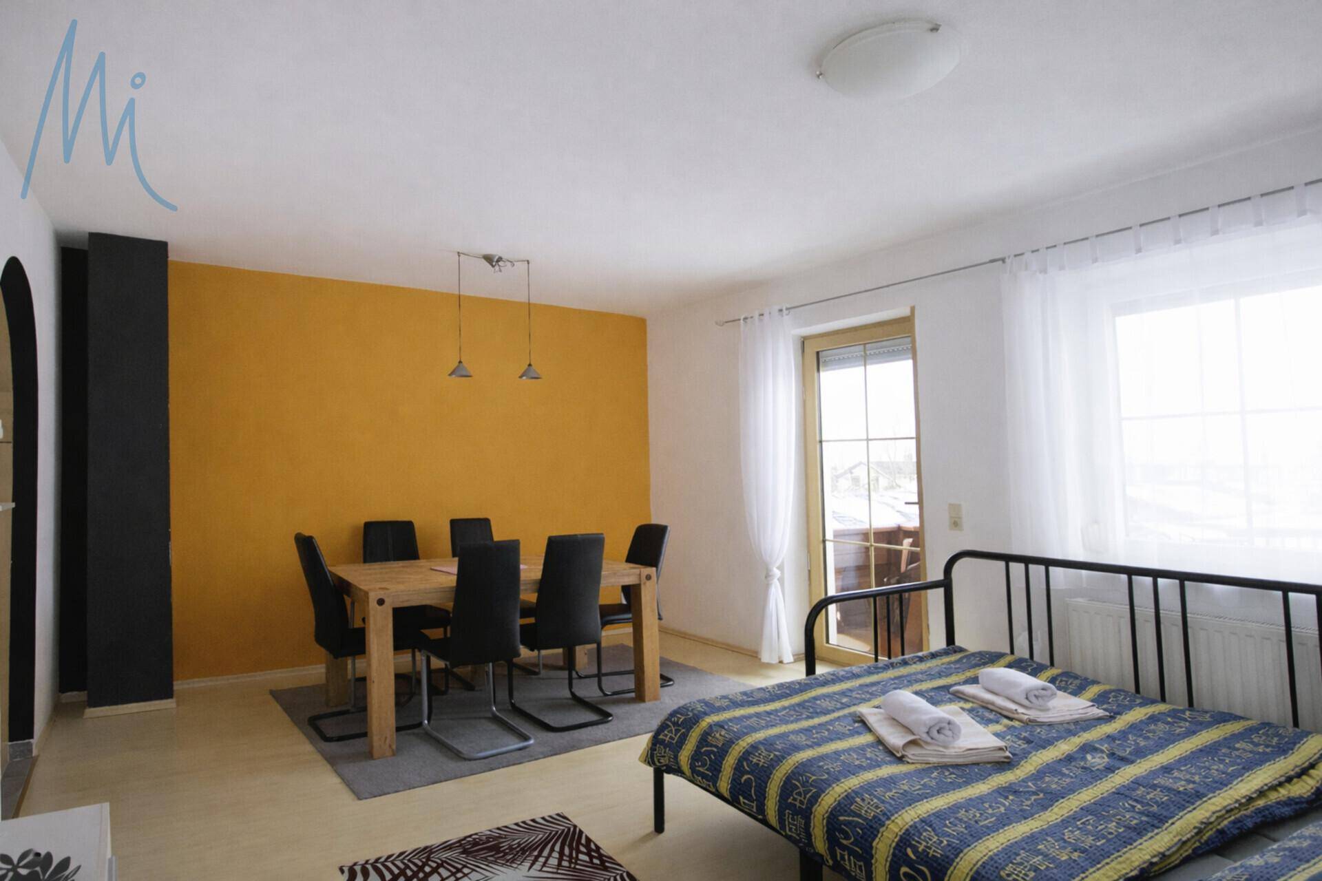 Geräumiger Wohn- und Essbereich mit Esstisch, Schlafsofa und Zugang zum Balkon.