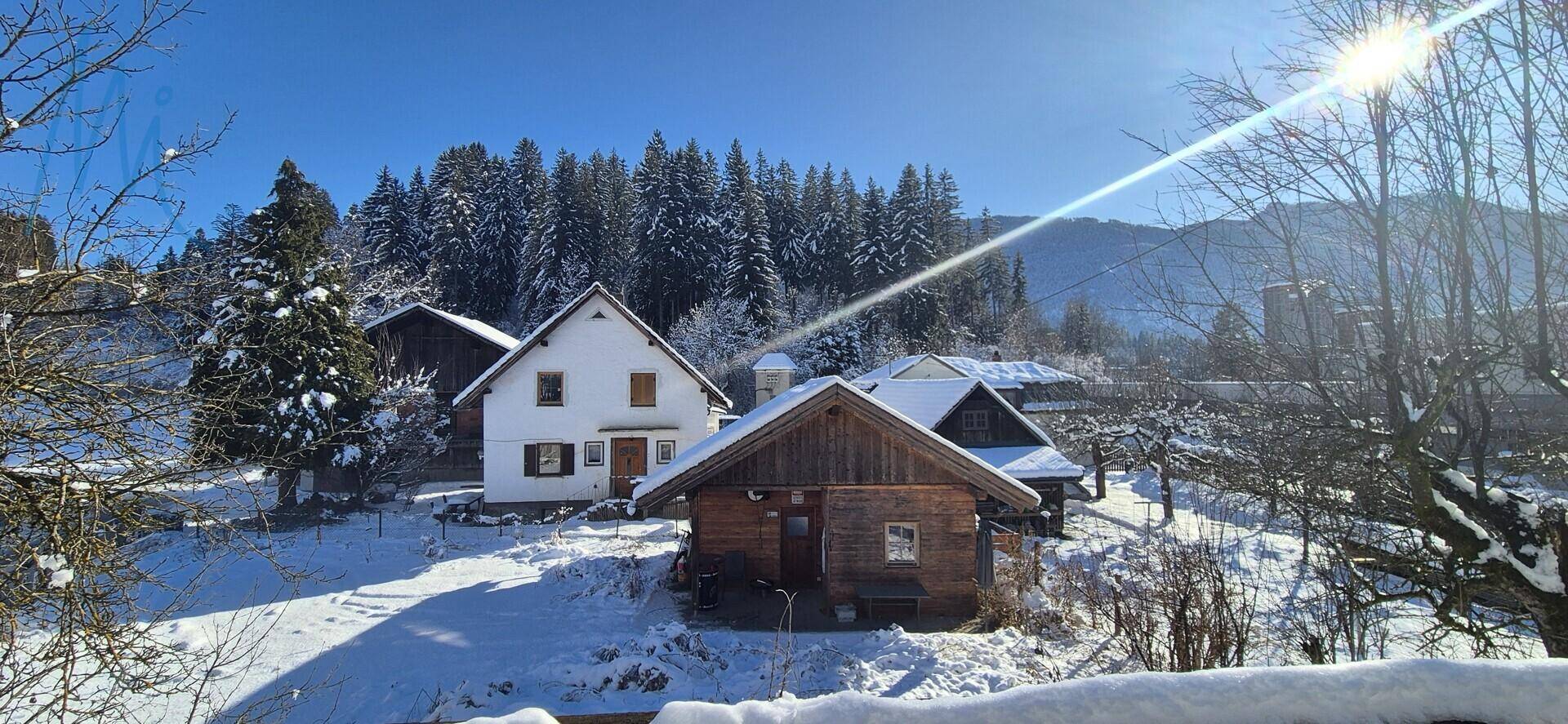 Winterliche Gesamtansicht des Anwesens mit mehreren Gebäuden und schneebedeckten Bäumen.