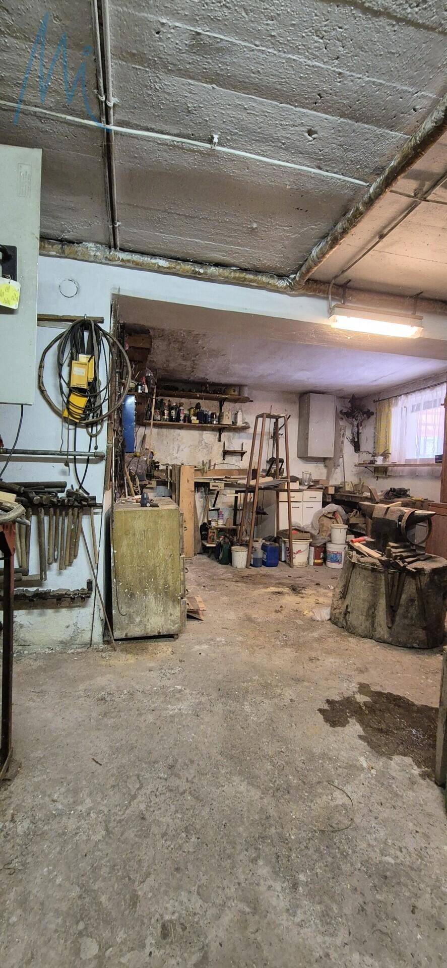 Werkstatt oder Abstellraum im Keller mit Betonboden und verschiedenen Werkzeugen.