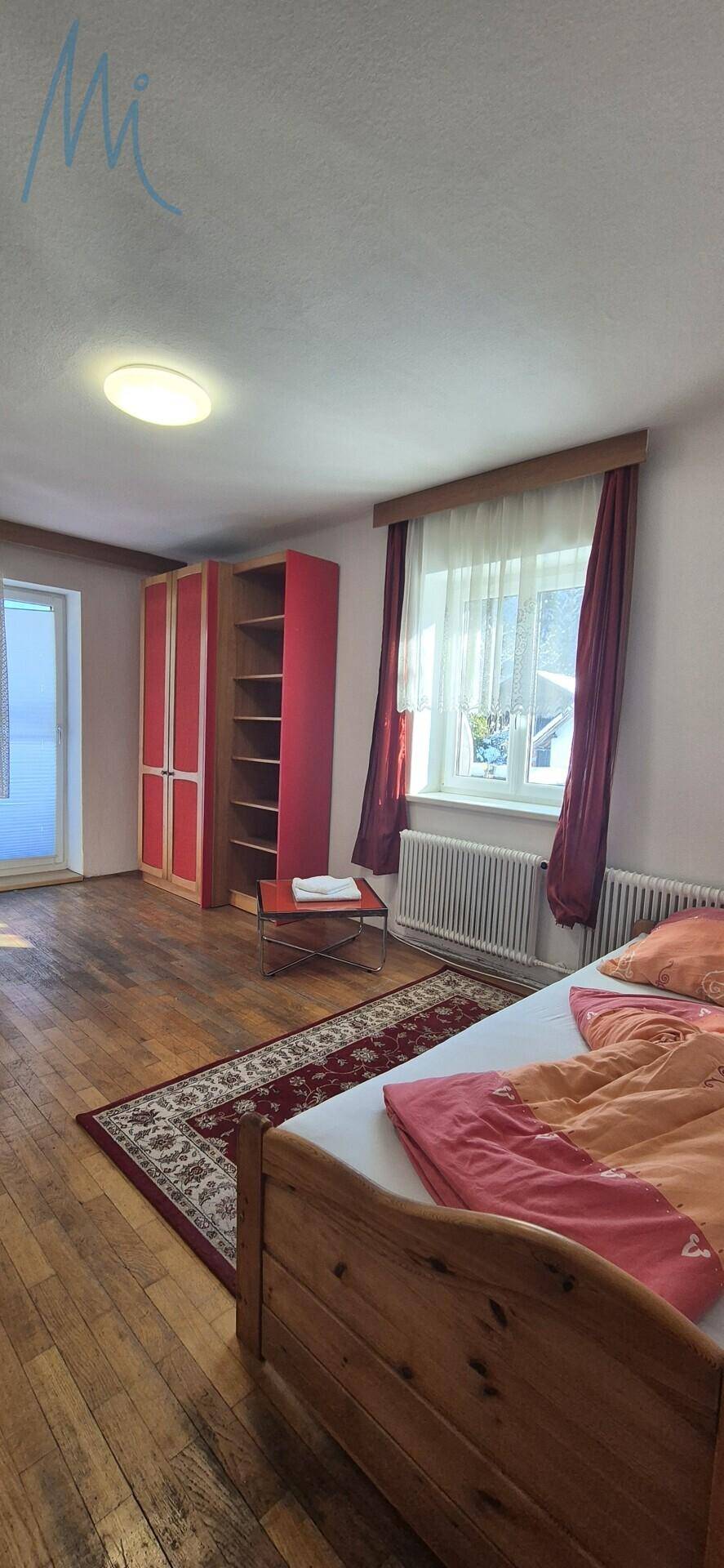 Geräumiges Schlafzimmer mit Holzboden, Einzelbett und Zugang zu einem Balkon.