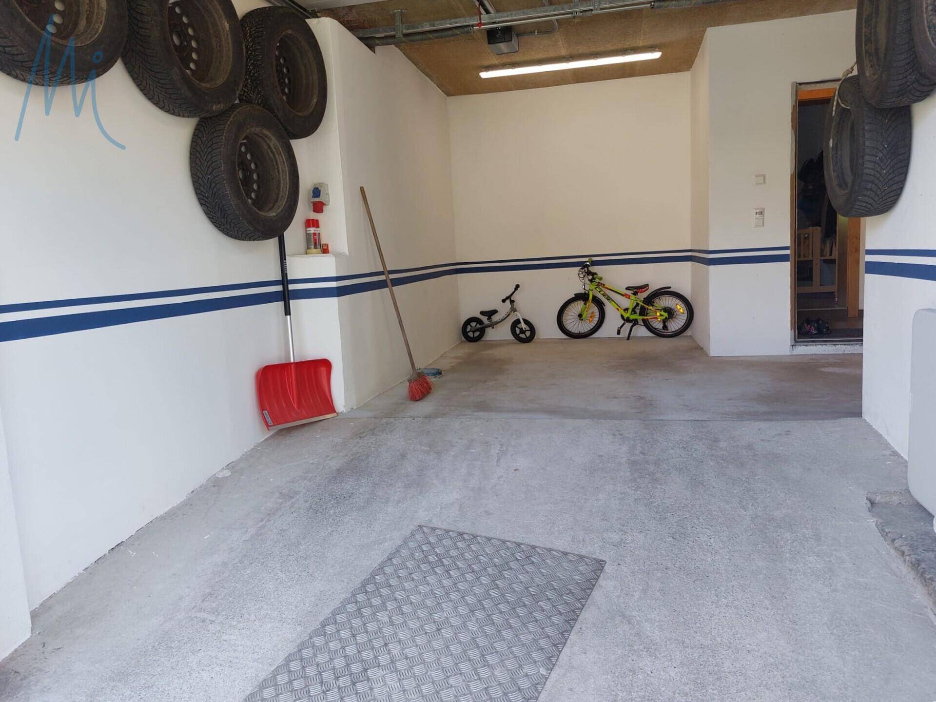 Geräumige Garage mit Betonboden, Stauraum für Reifen und Fahrrädern.