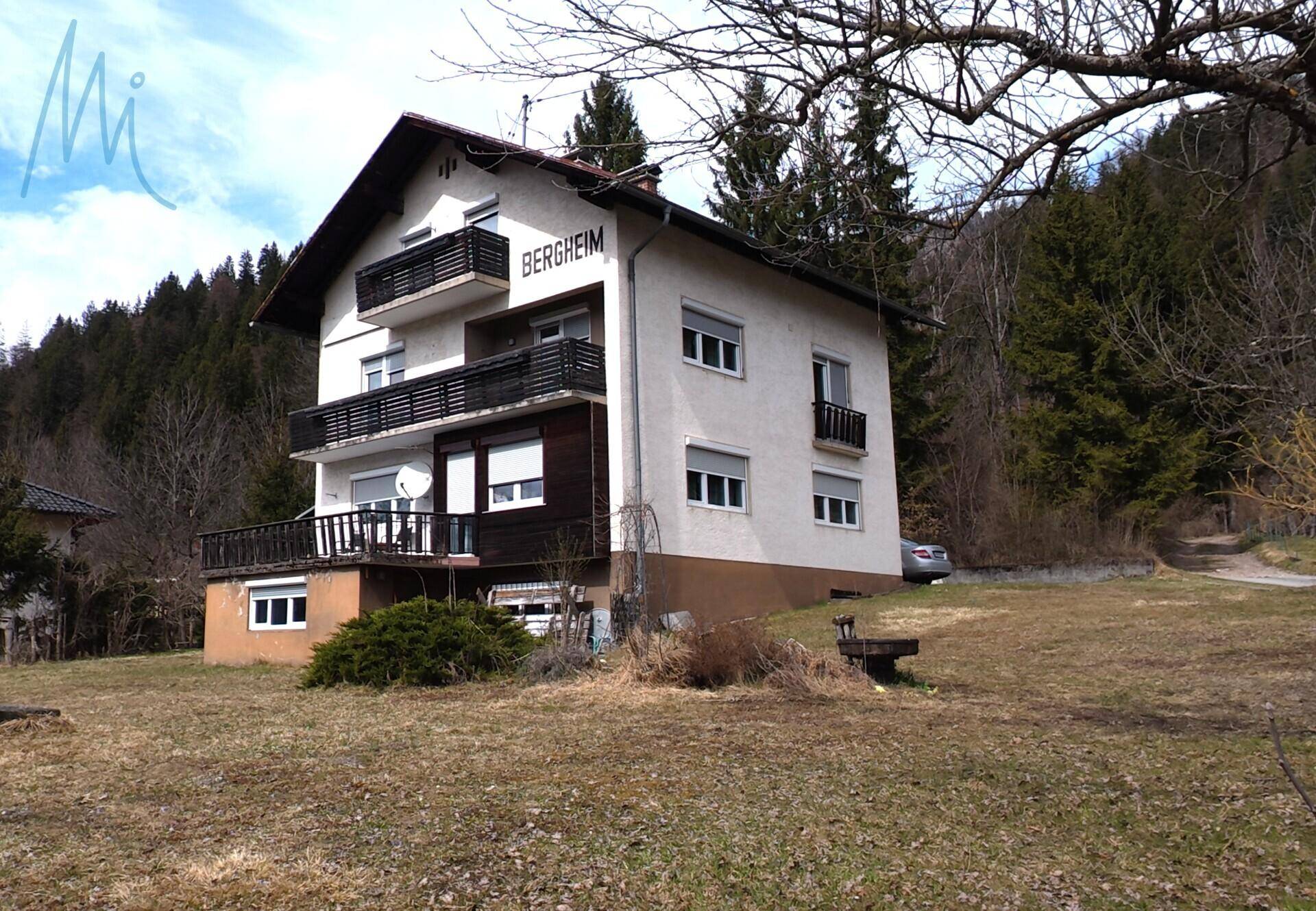 Wohnhaus mit Balkonen und weitläufigem Grundstück in ländlicher Umgebung.