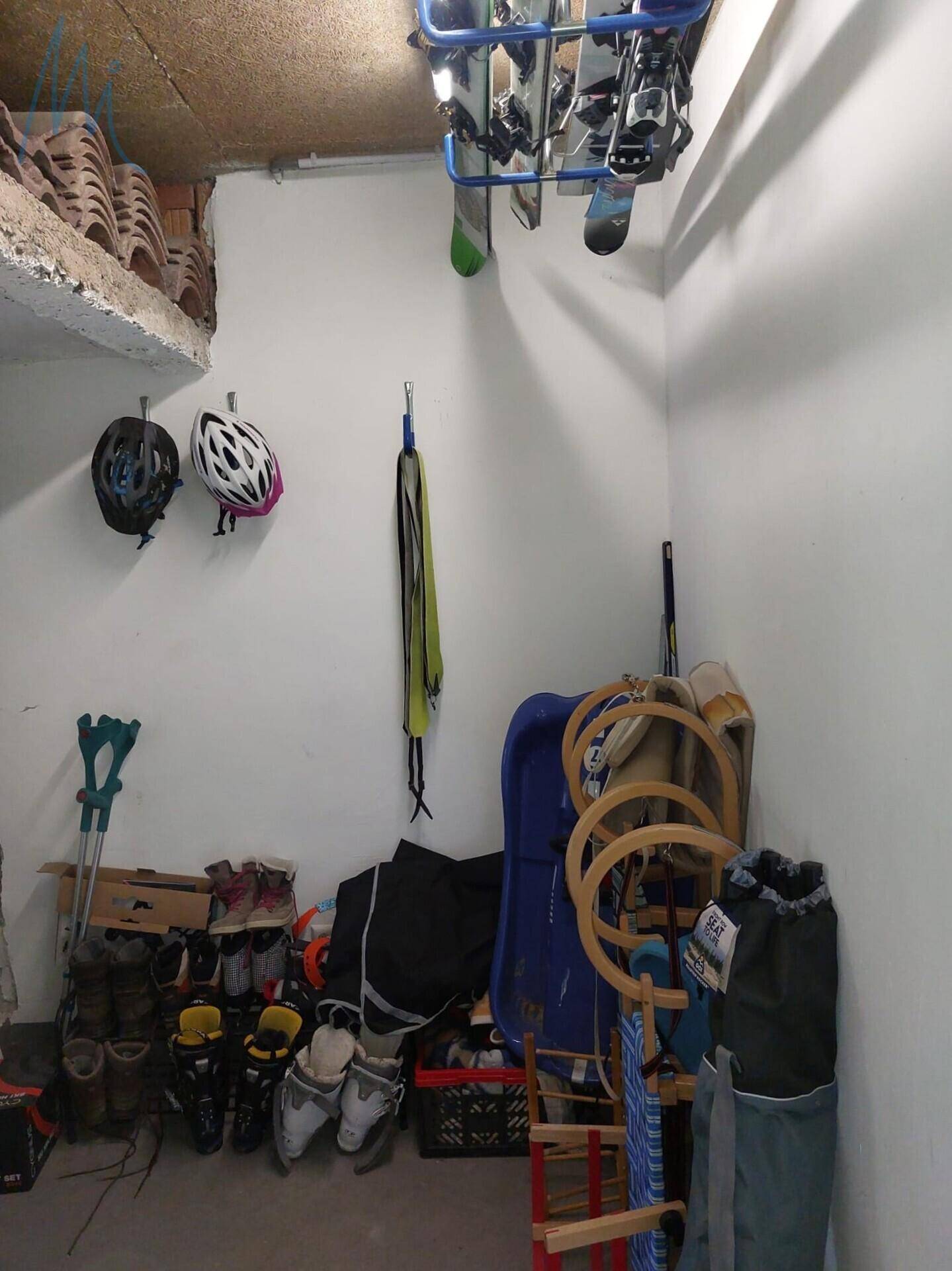 Abstellraum für Sportausrüstung und Wintergeräte mit Regalen und Haken.