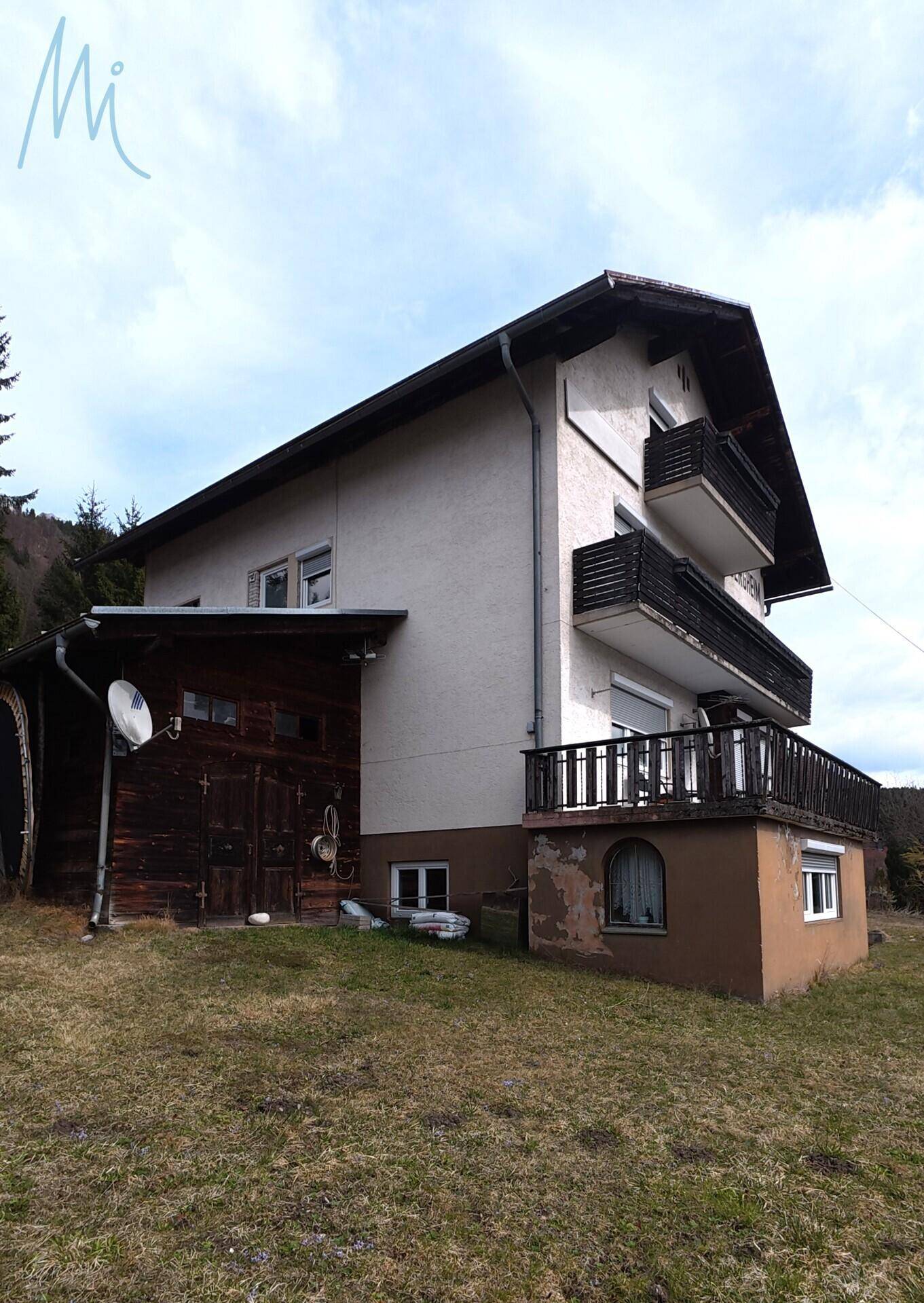 Seitenansicht des Wohnhauses mit Balkonen und angrenzendem Schuppen.