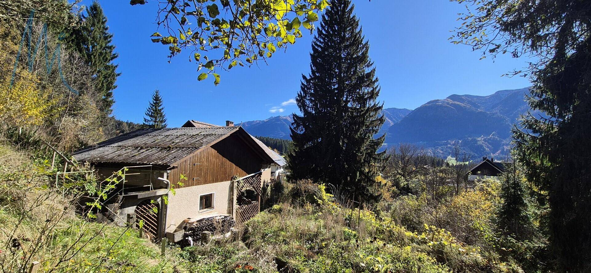 Haus in ländlicher Umgebung mit Bergblick und umgeben von Bäumen und Natur.