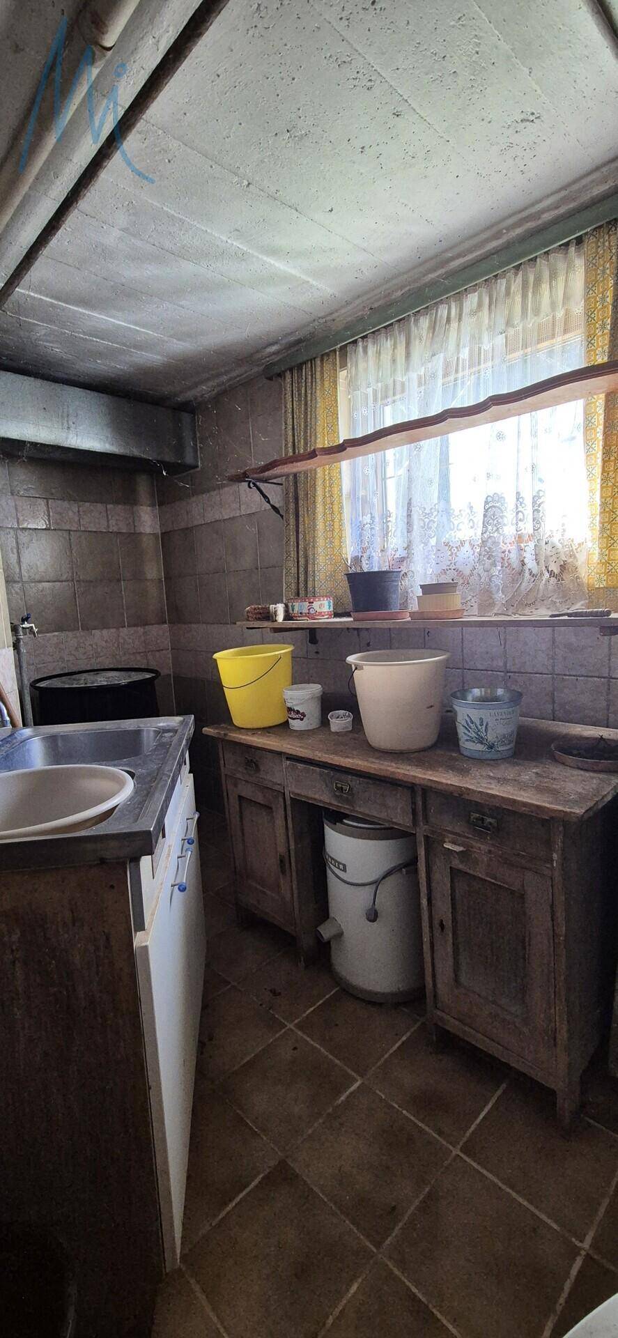 Einfacher Waschraum oder Abstellraum im Keller mit Spülbecken und Holzmöbeln.