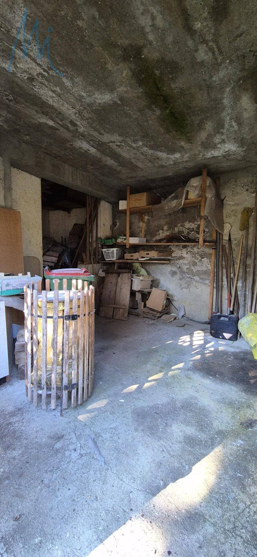 Unaufgeräumter Kellerraum mit Betonboden und -decke, der als Abstellfläche dient.