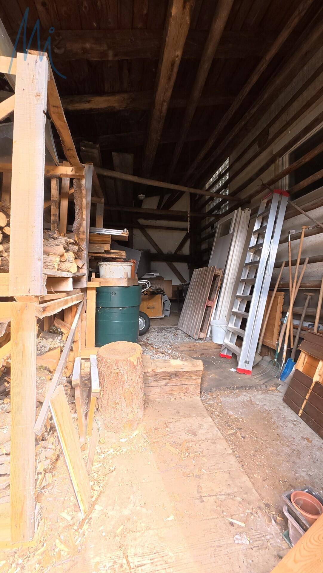 Rustikaler Innenraum eines Nebengebäudes mit Holzbalken und Lagerflächen.