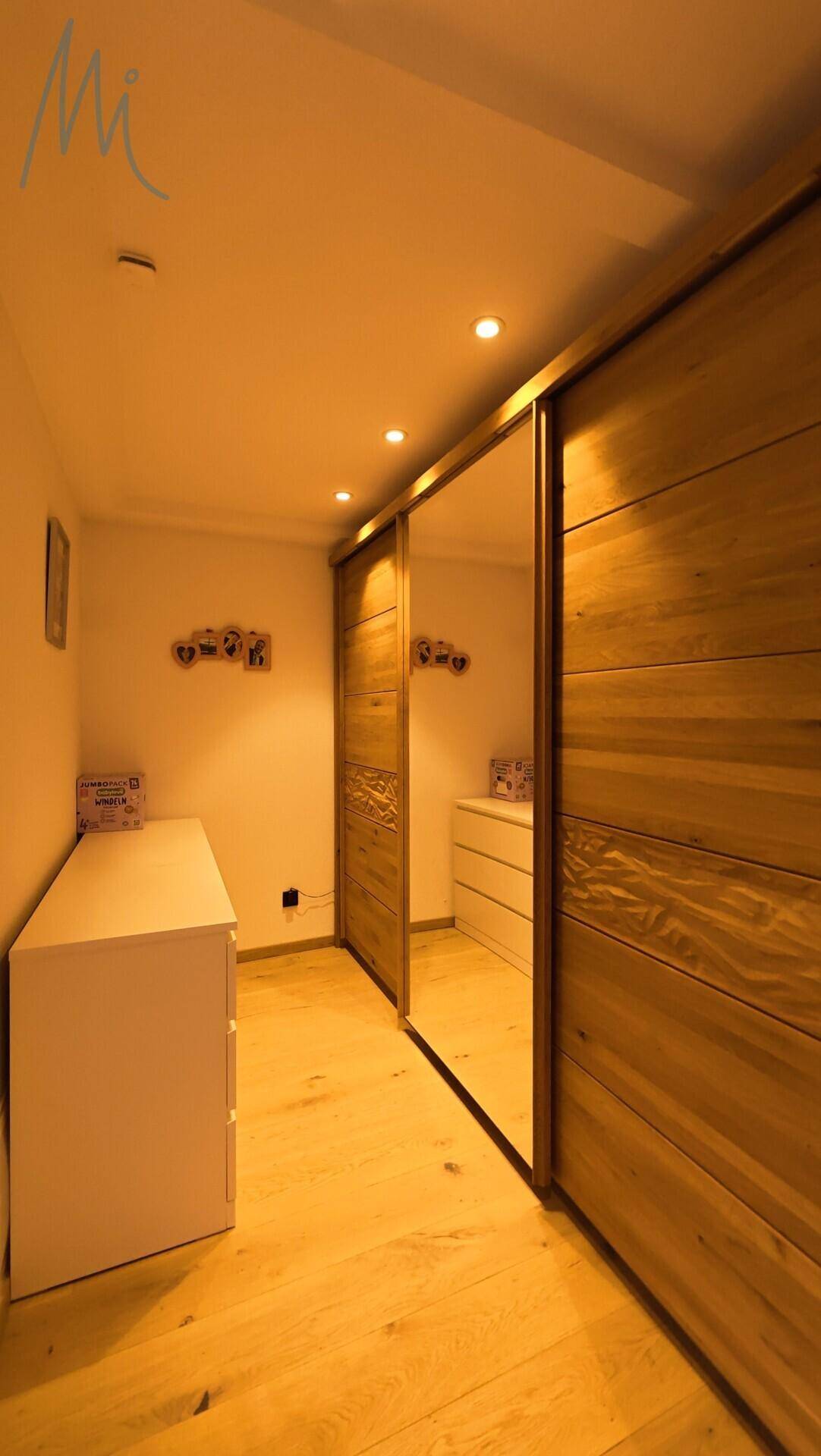 Schlafzimmer mit Holzboden und maßgefertigten Einbauschränken mit Spiegeltüren.