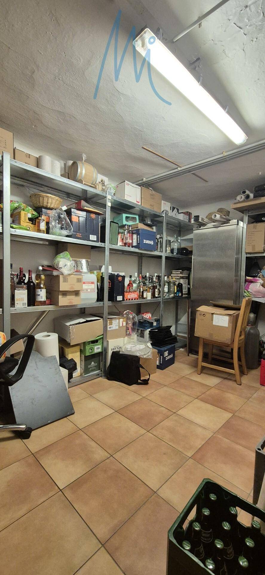 Geräumiger Lagerraum mit Metallregalen, Fliesenboden und verschiedenen Vorräten, gut organisiert.