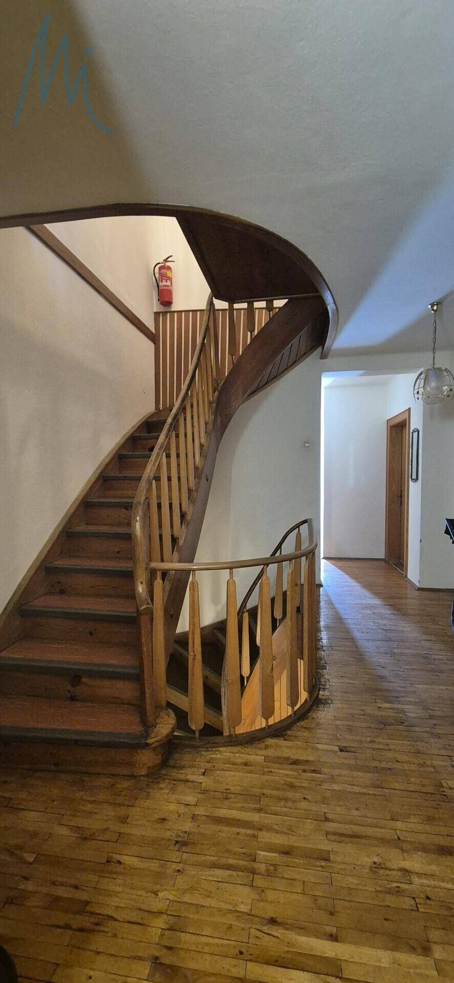 Geräumiger Flur mit geschwungener Holztreppe und Parkettboden.