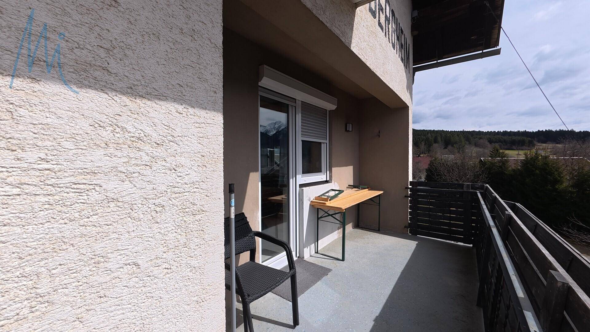 Kleiner Balkon mit Holztisch und Blick auf die Umgebung.