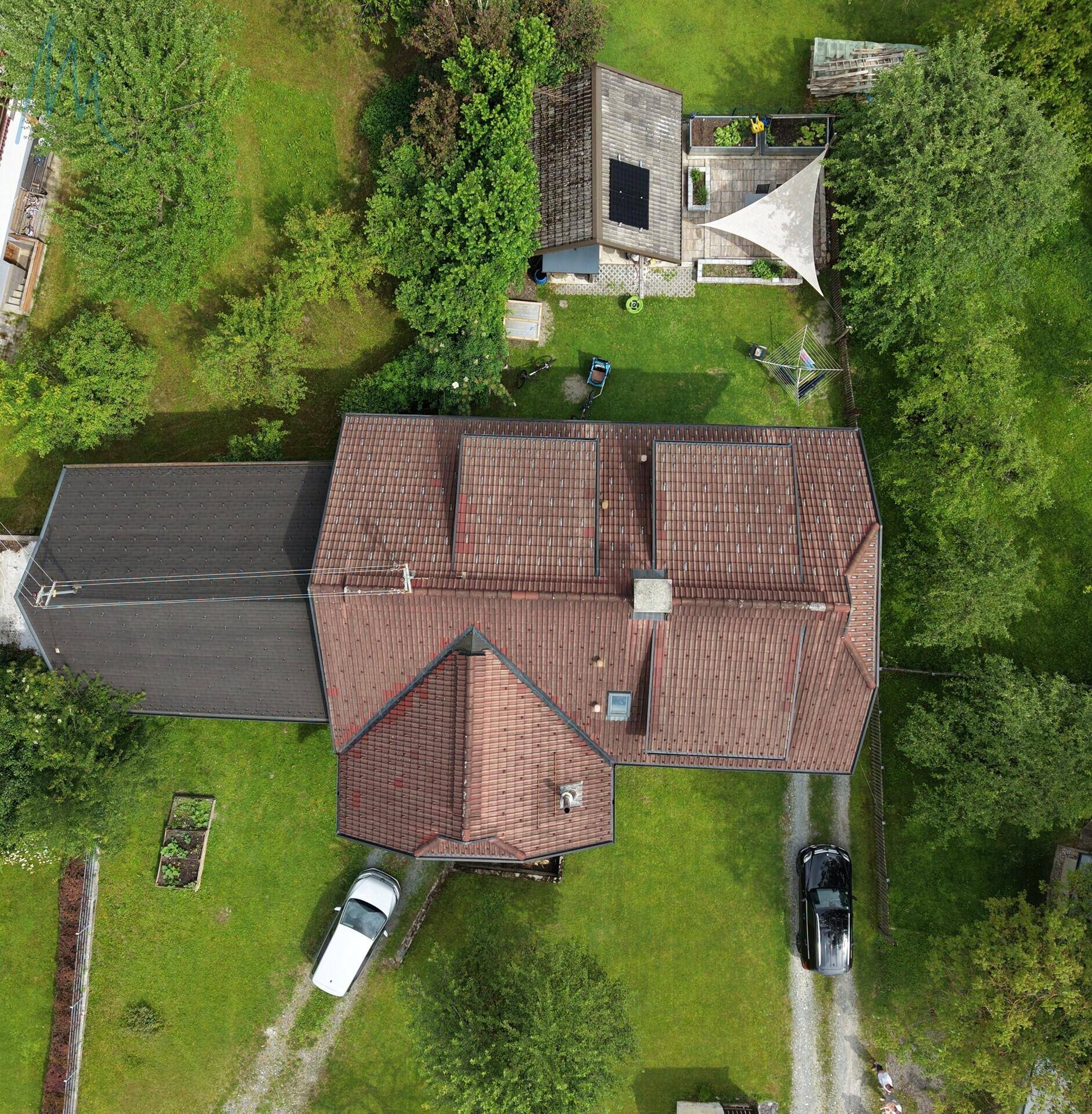 Vogelperspektive des Hauses mit Satteldach, großem Grundstück und Zufahrt, umgeben von Bäumen.