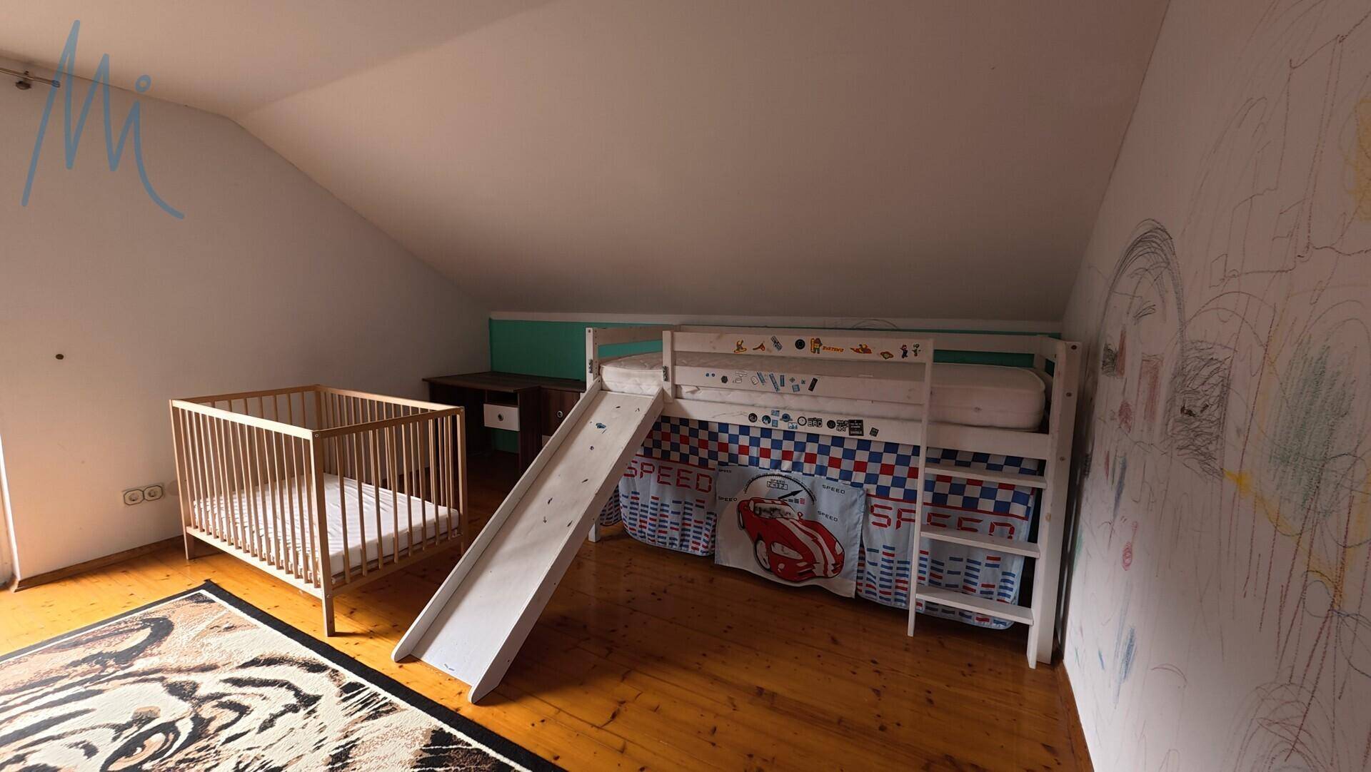 Kinderzimmer im Dachgeschoss mit Hochbett, Rutsche und Babybett.
