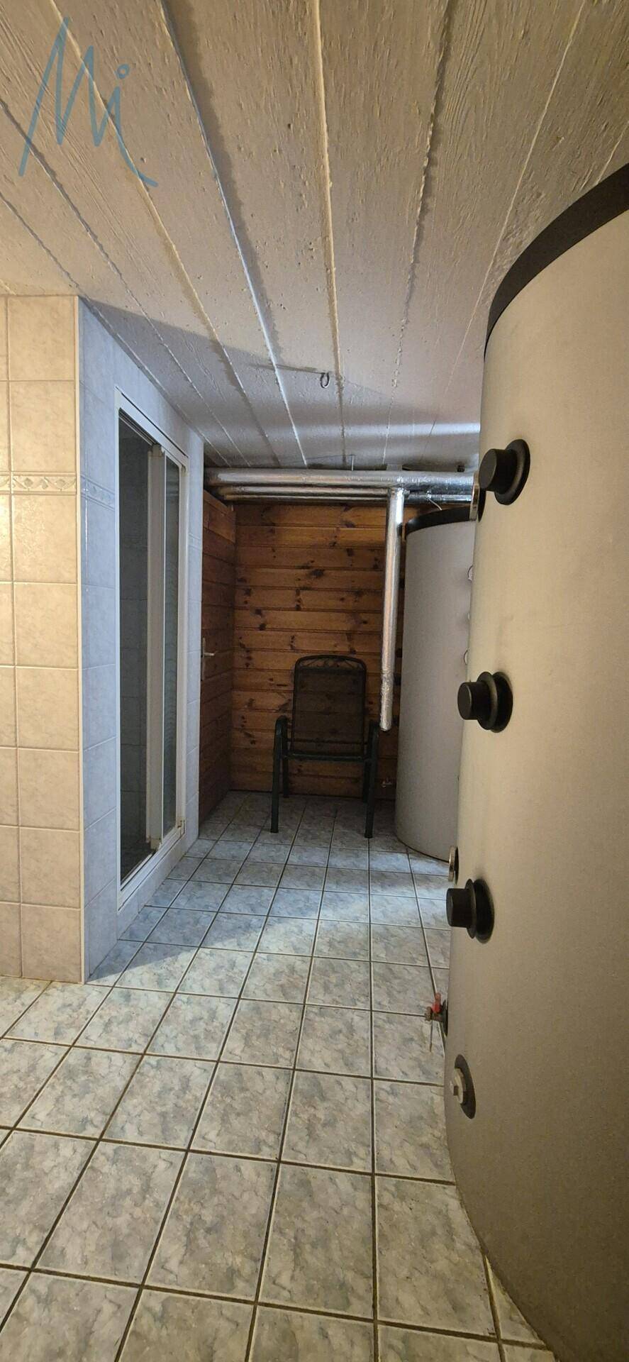 Kellerraum mit Warmwasserspeicher, Duschkabine und Fliesenboden.