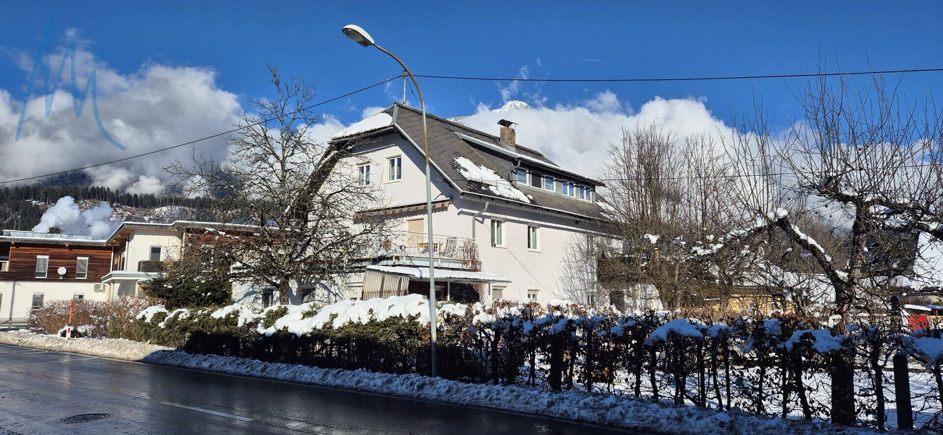 Winterliche Ansicht des Hauses mit schneebedeckter Umgebung und Bergen im Hintergrund.