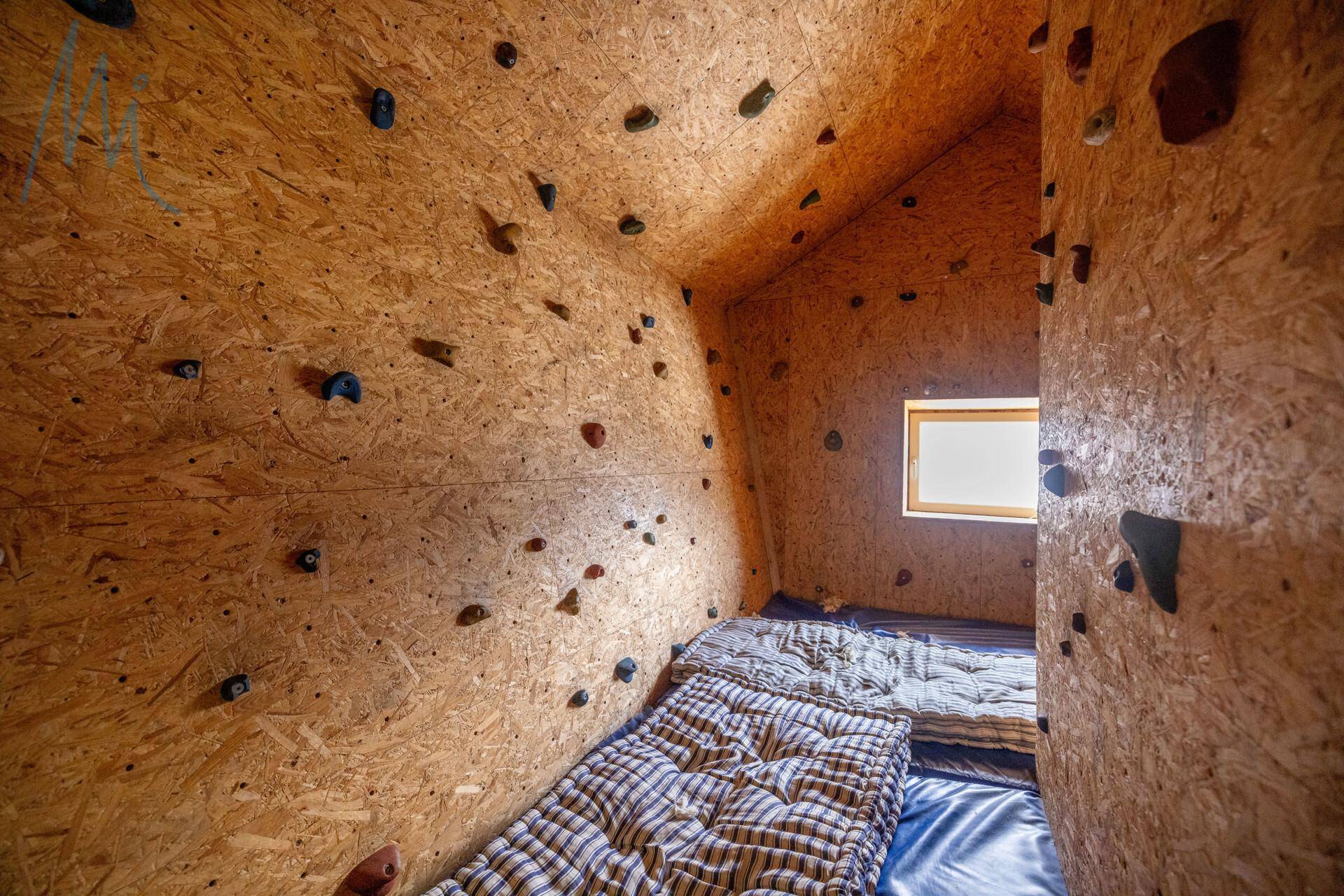 Einzigartiger Kletterraum mit OSB-Plattenwänden und Matten auf dem Boden, ideal für Sportbegeisterte.