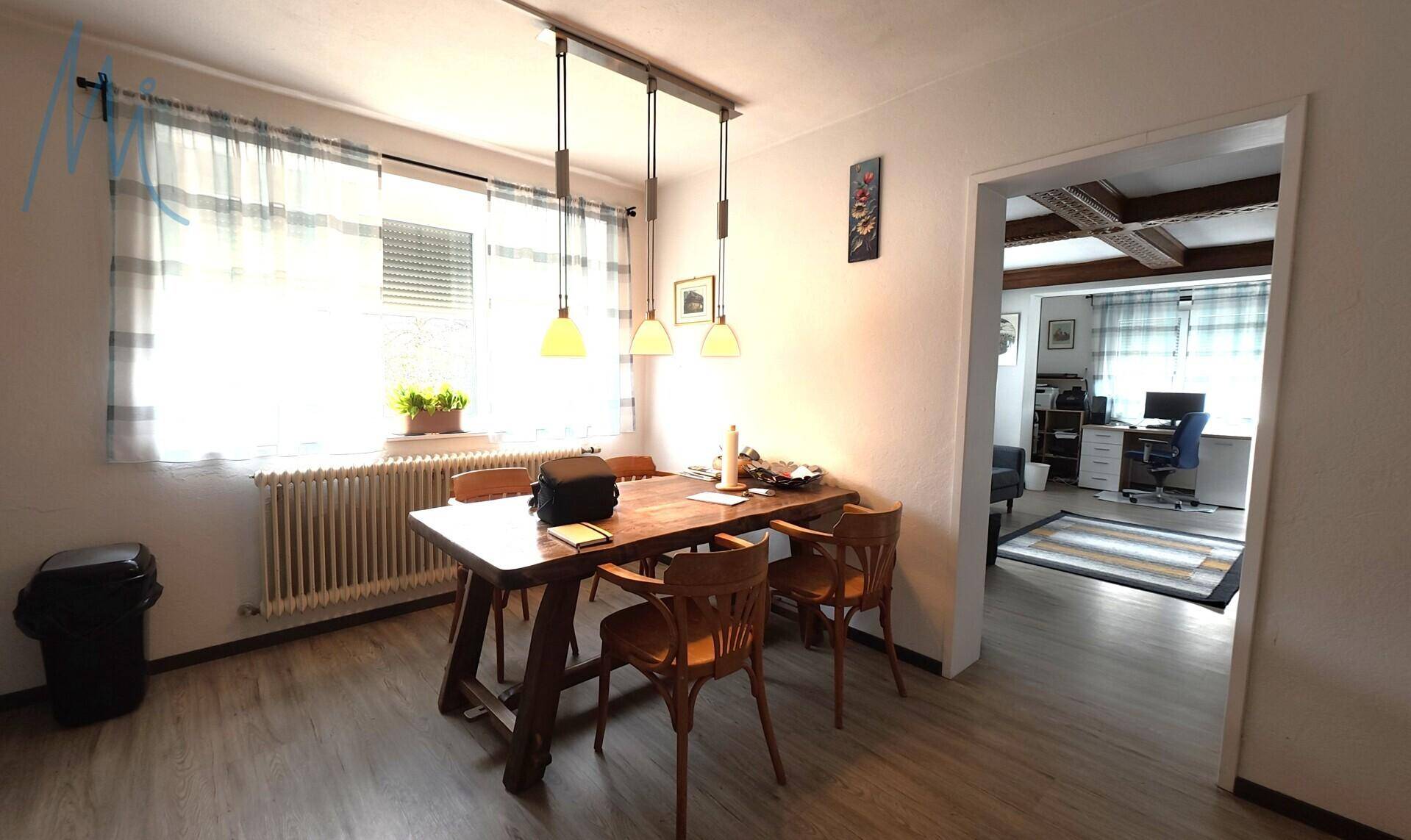 Essbereich mit Holztisch und Stühlen, offen zum Wohnzimmer und mit Blick nach draußen.