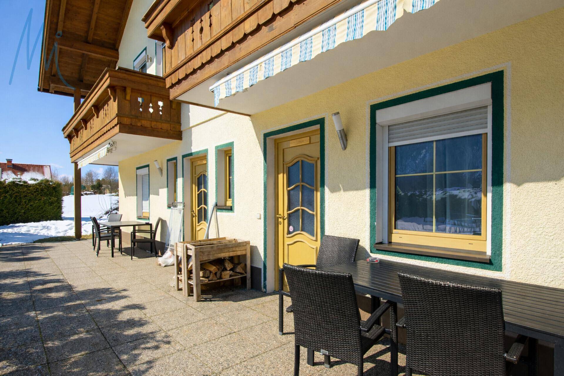 Gemütliche Terrasse mit Outdoor-Sitzgelegenheiten und Blick auf die verschneite Landschaft.