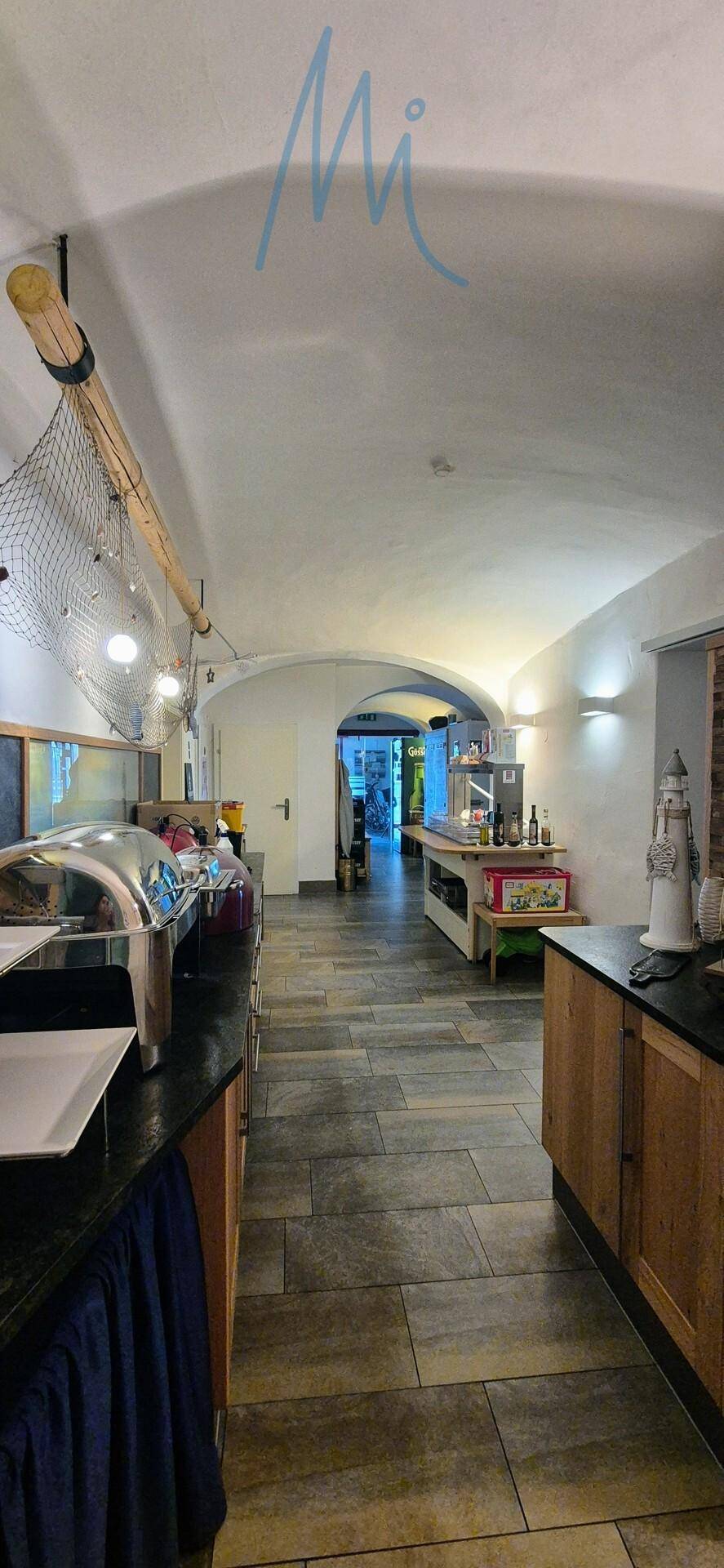 Langer Flur mit gewölbter Decke, Fliesenboden und Buffetstationen, ideal für Speisenpräsentation.