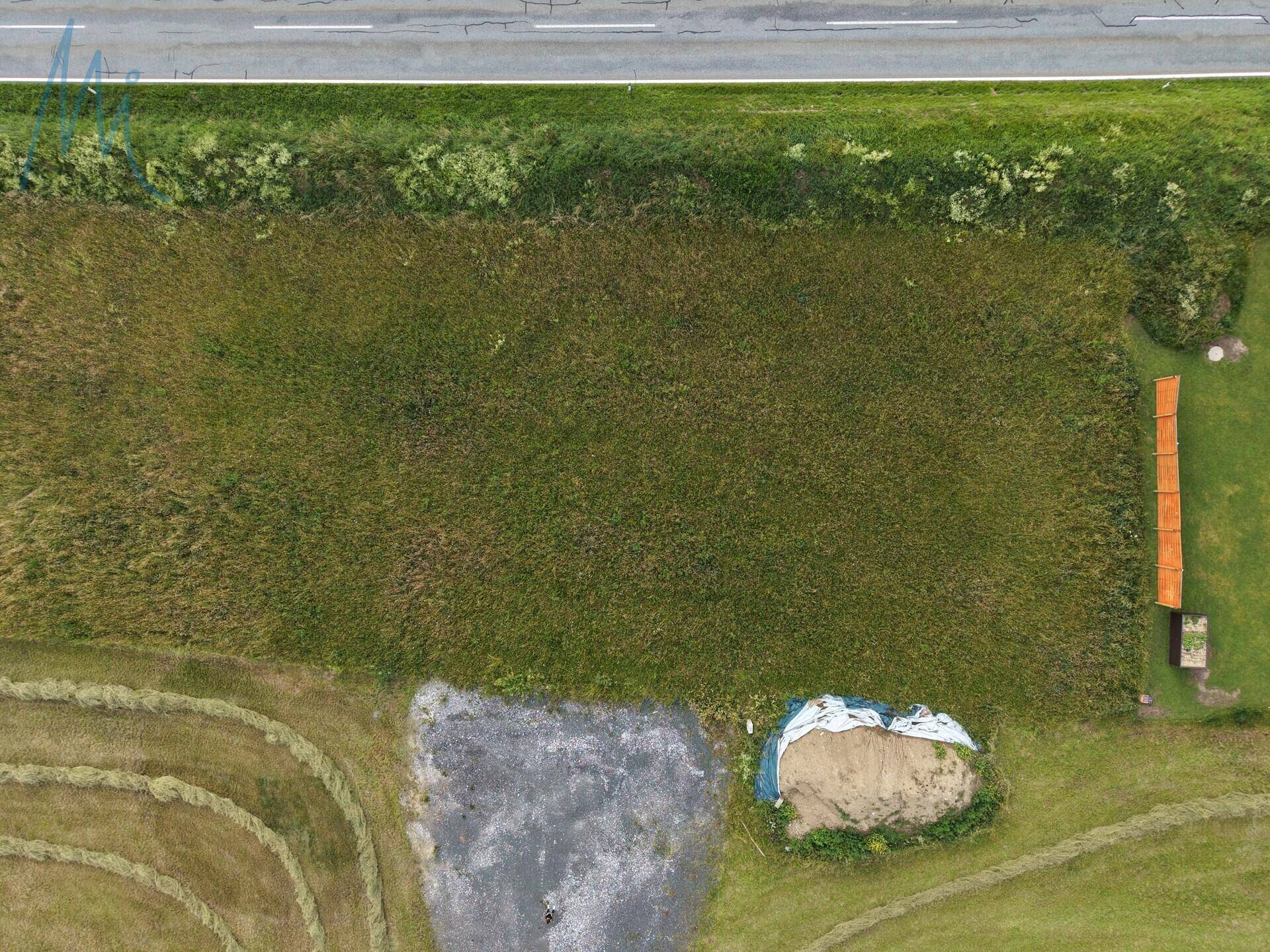 Luftaufnahme eines weitläufigen grünen Grundstücks mit angrenzender Straße und ländlicher Umgebung.