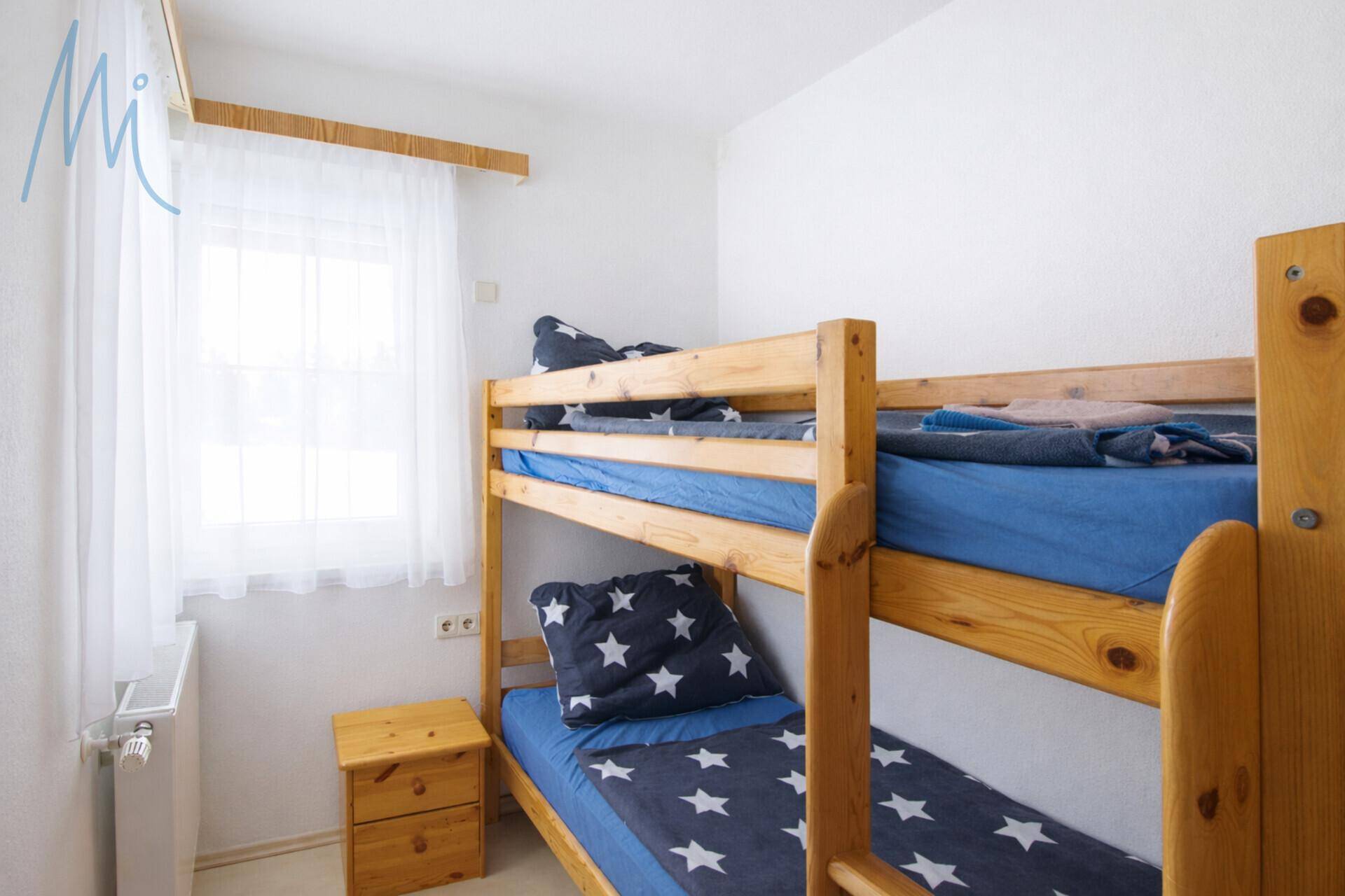 Kinderzimmer mit Etagenbett aus Holz und hellem Fenster, ideal für Gäste.