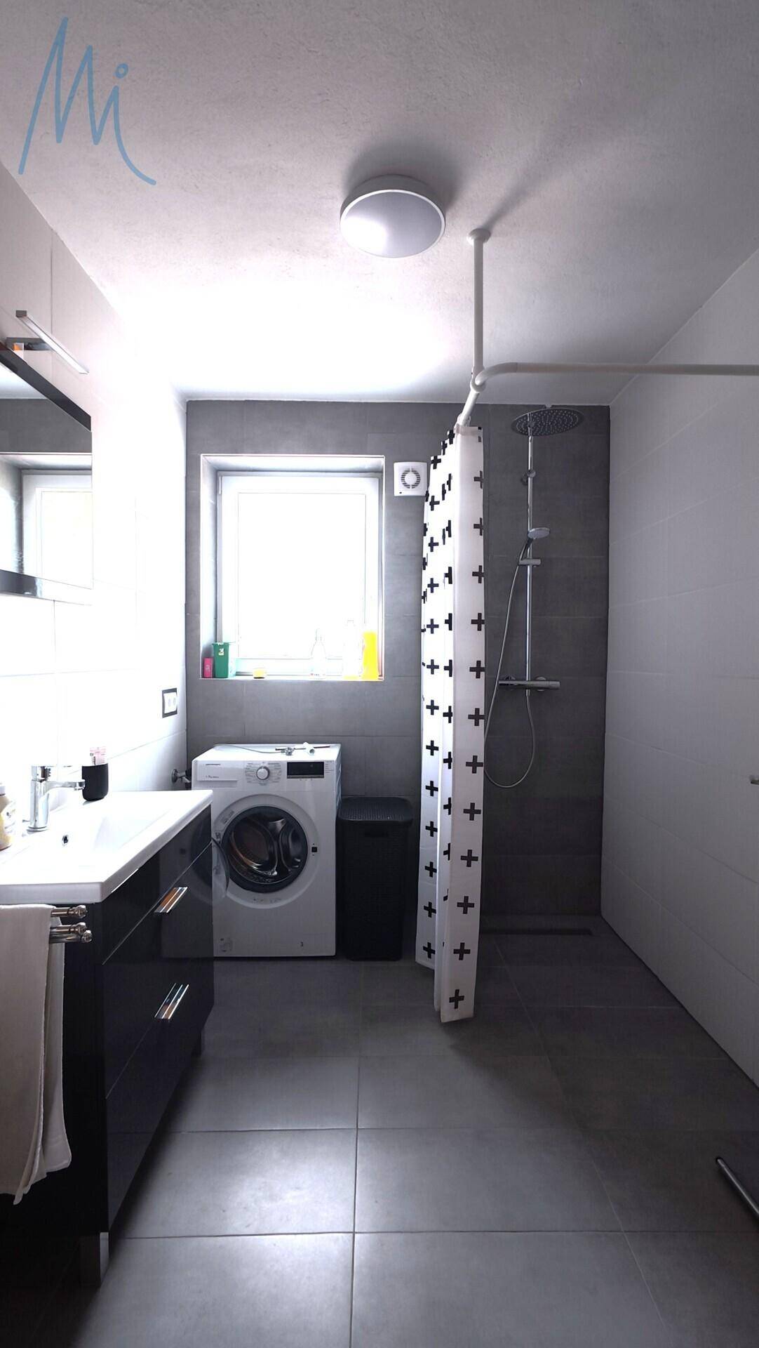 Modernes Badezimmer mit Dusche, Waschmaschine und Fenster.