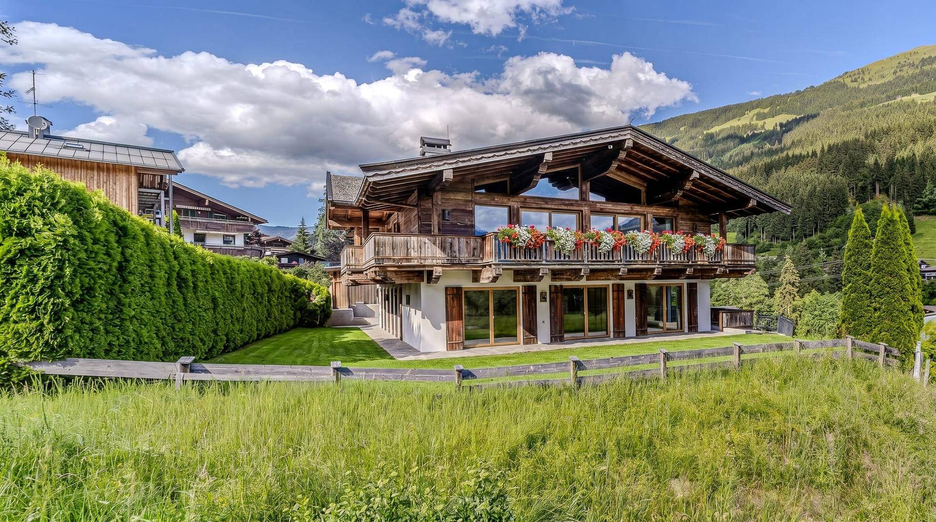 Idyllisches Holzchalet eingebettet in eine grüne Landschaft mit gepflegtem Rasen und Bergblick.