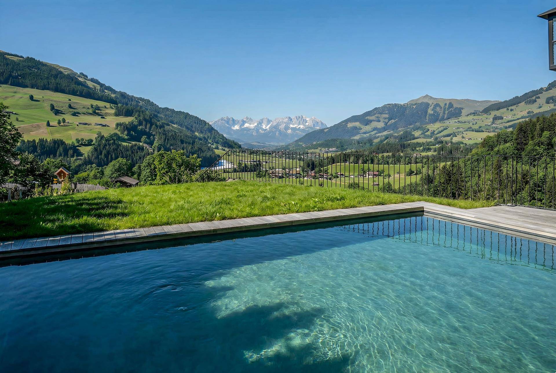 Infinity-Pool mit atemberaubendem Bergblick und sonniger Lage in der alpinen Landschaft.