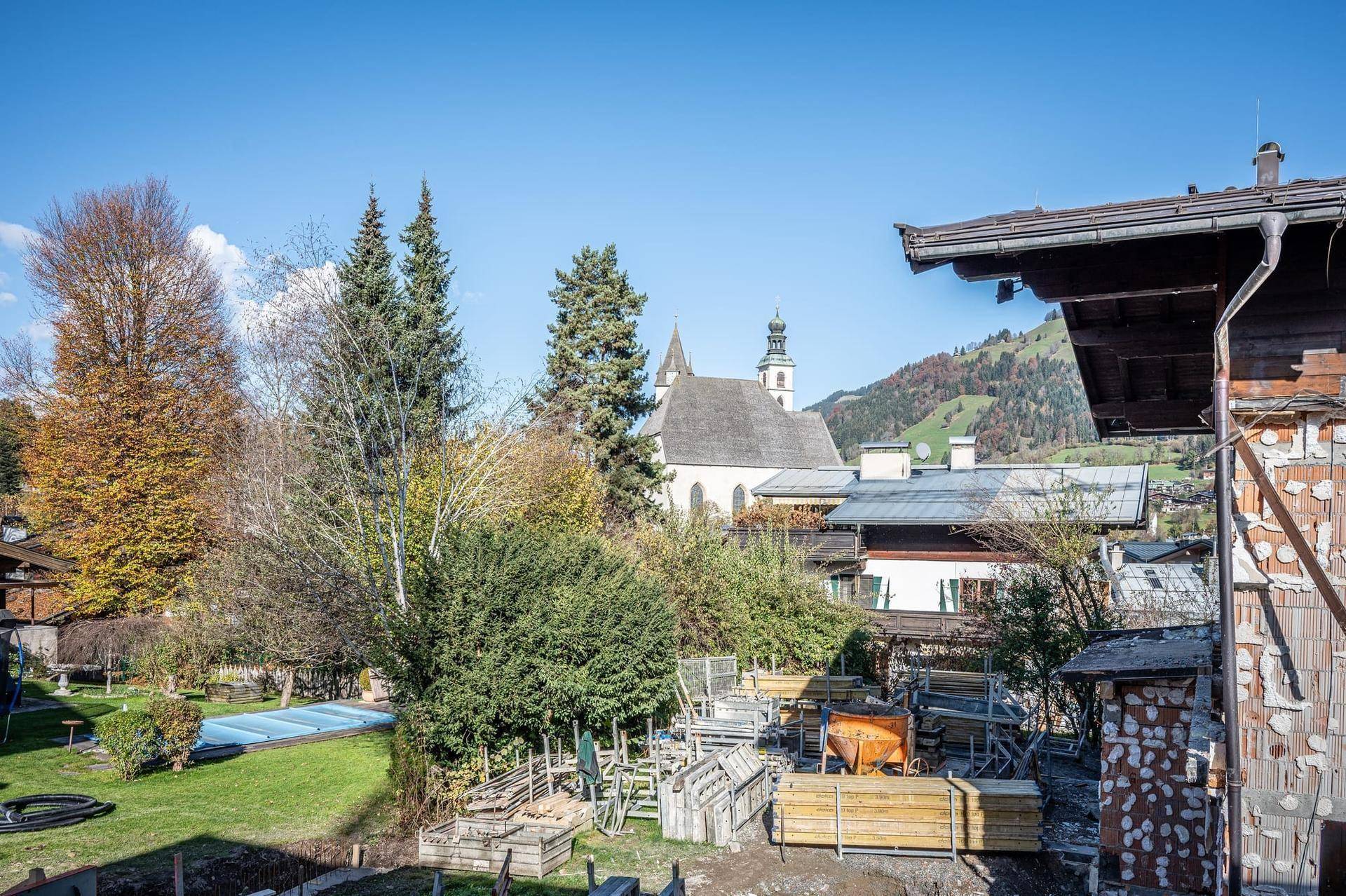 Blick auf die Dorfkirche und die herbstliche Landschaft mit Bäumen und einem kleinen Teich.