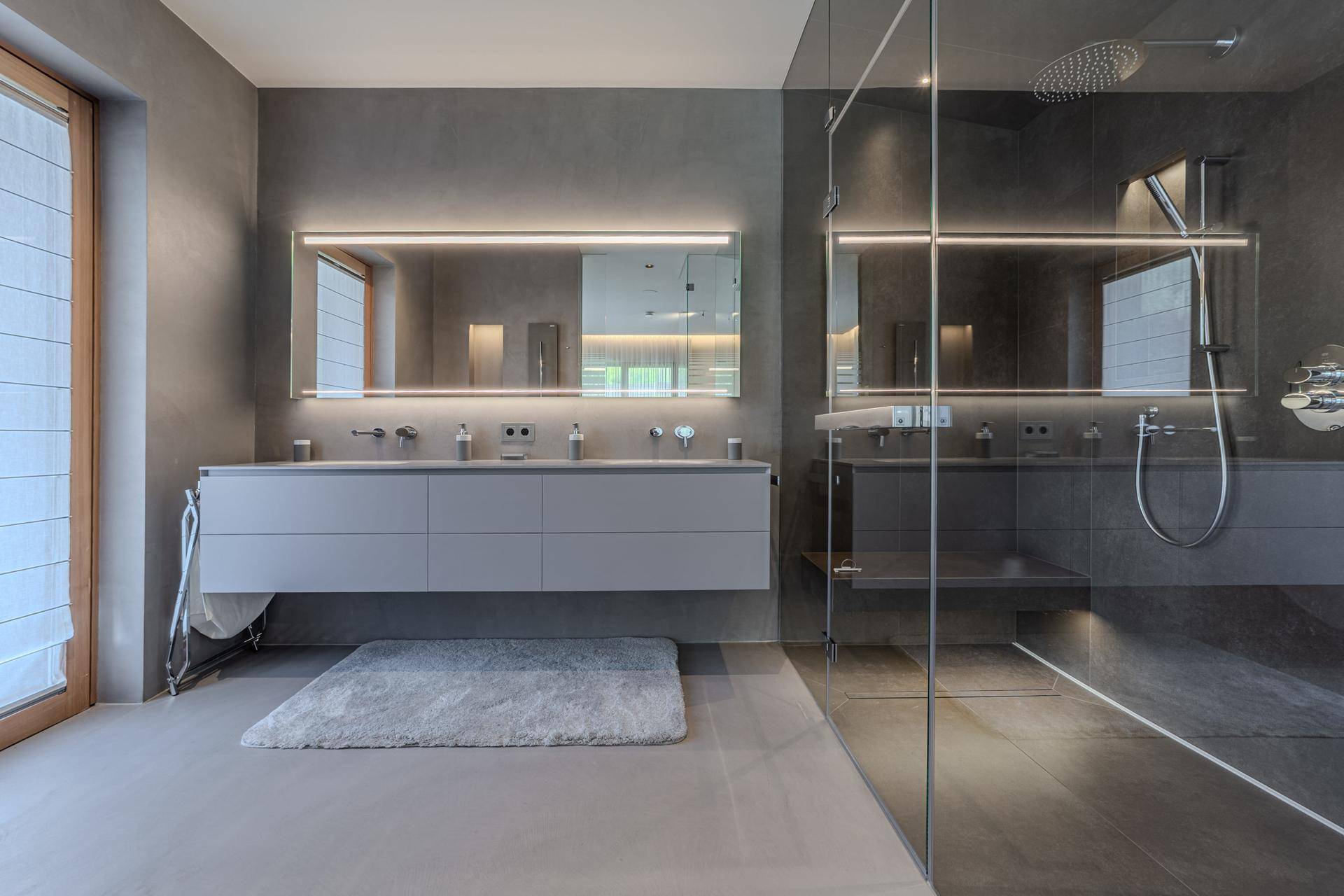 Modernes Badezimmer mit Doppelwaschbecken, großer begehbarer Dusche und indirekter Beleuchtung.