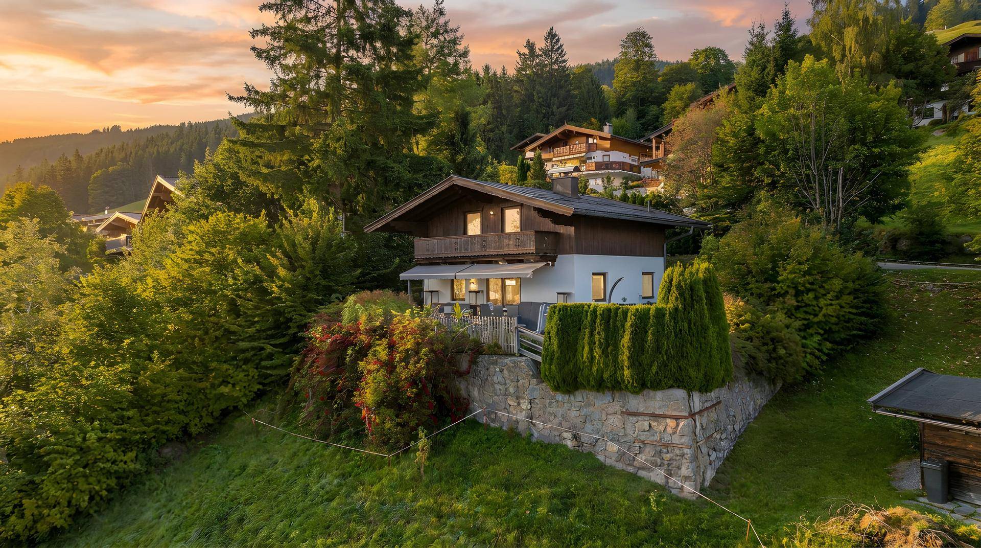 Einzelnes Haus in Hanglage mit Terrasse und gepflegter Bepflanzung bei warmem Abendlicht.