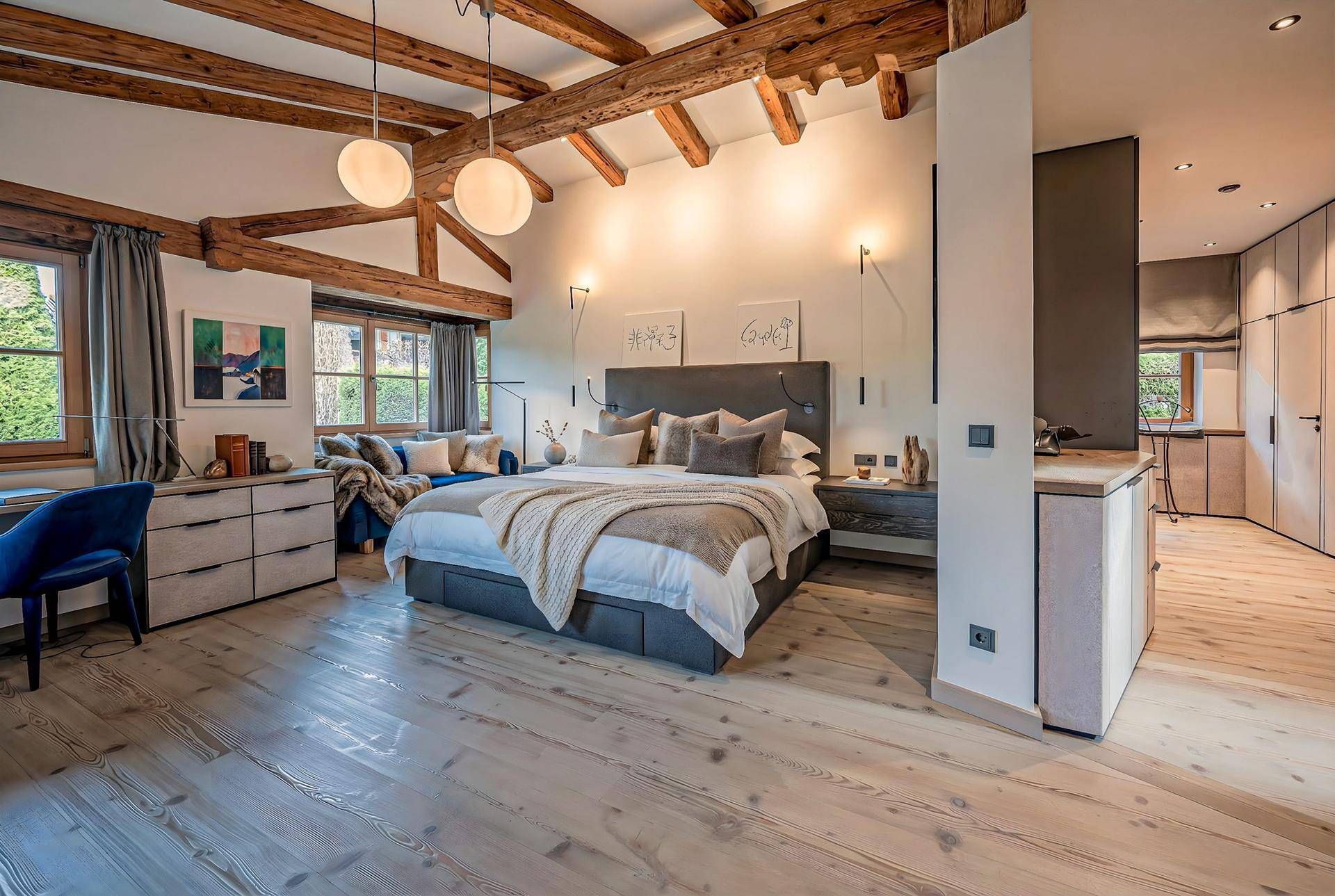 Helles Schlafzimmer mit Holzbalken, großem Bett und gemütlicher Sitzecke, bietet viel natürlichen Lichteinfall.