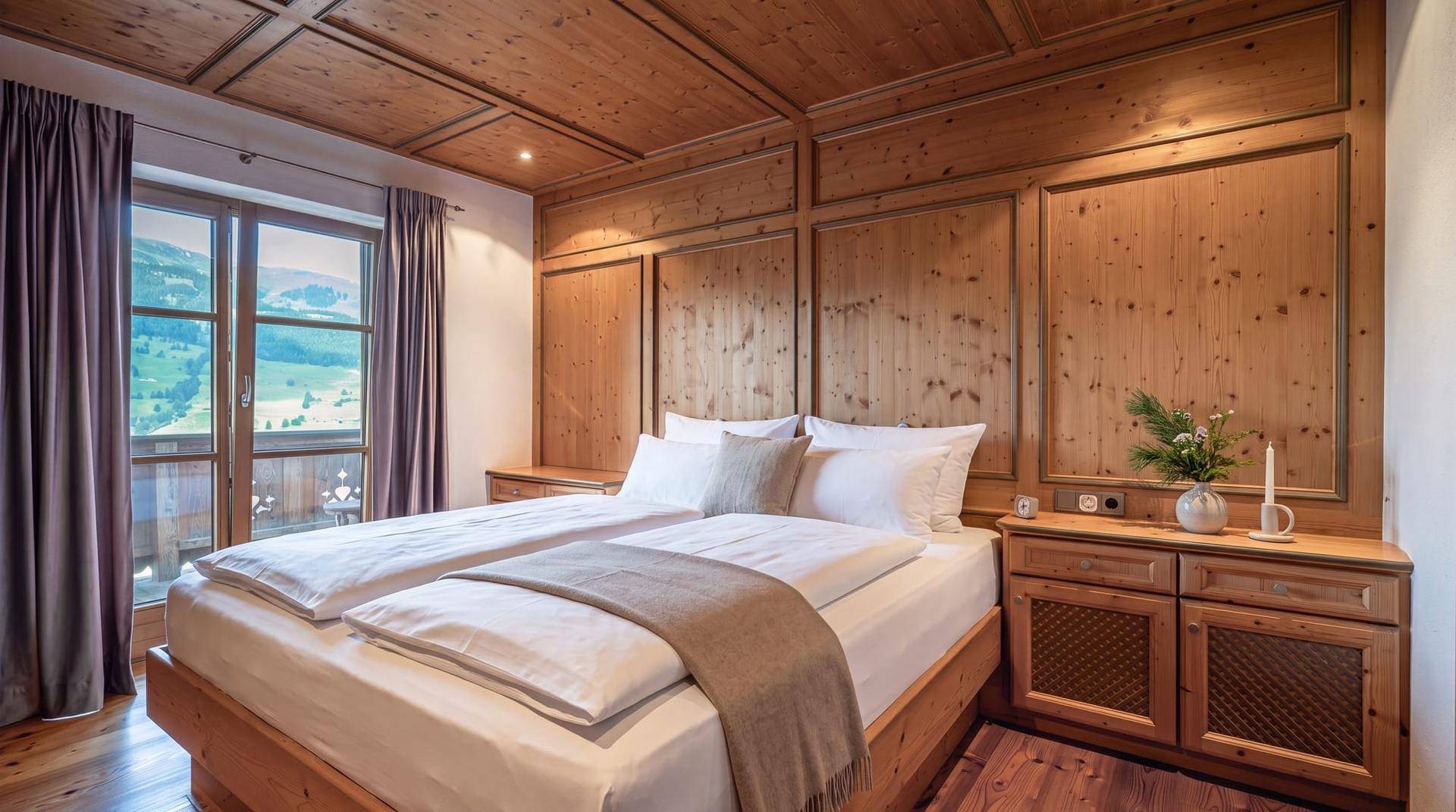 Komfortables Schlafzimmer mit viel Holz, einem Doppelbett und Zugang zu einem Balkon mit Bergblick.