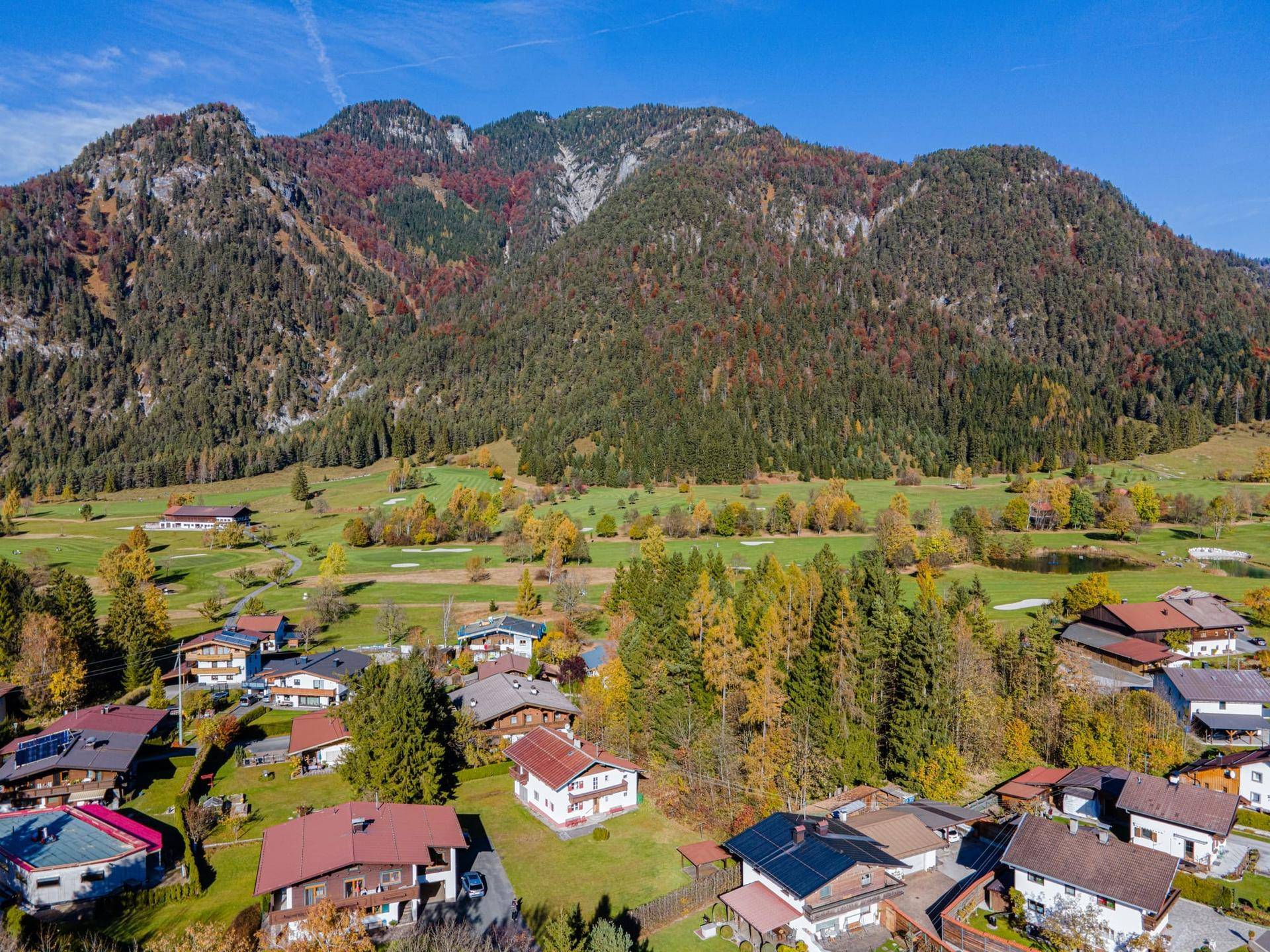 Panoramablick auf die malerische Alpenlandschaft mit Häusern und herbstlicher Vegetation.