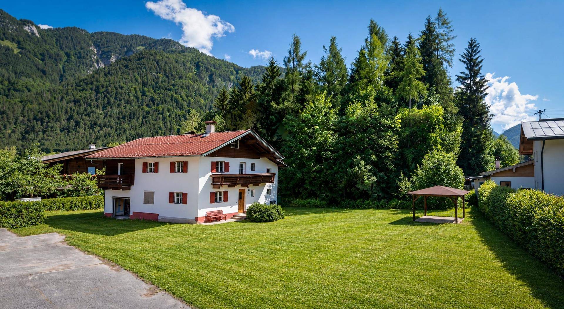 Panoramablick auf das Landhaus mit großem Garten, Pavillon und beeindruckender Bergkulisse.