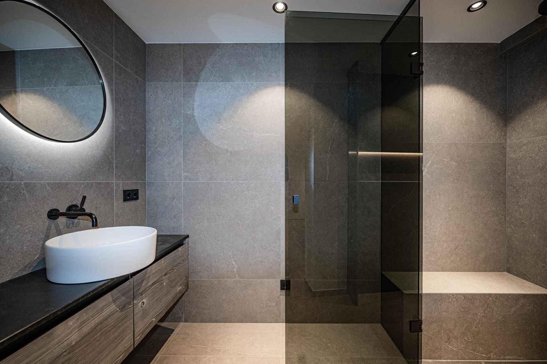 Modernes Badezimmer mit grauen Fliesen, Aufsatzwaschbecken und großer begehbarer Dusche.