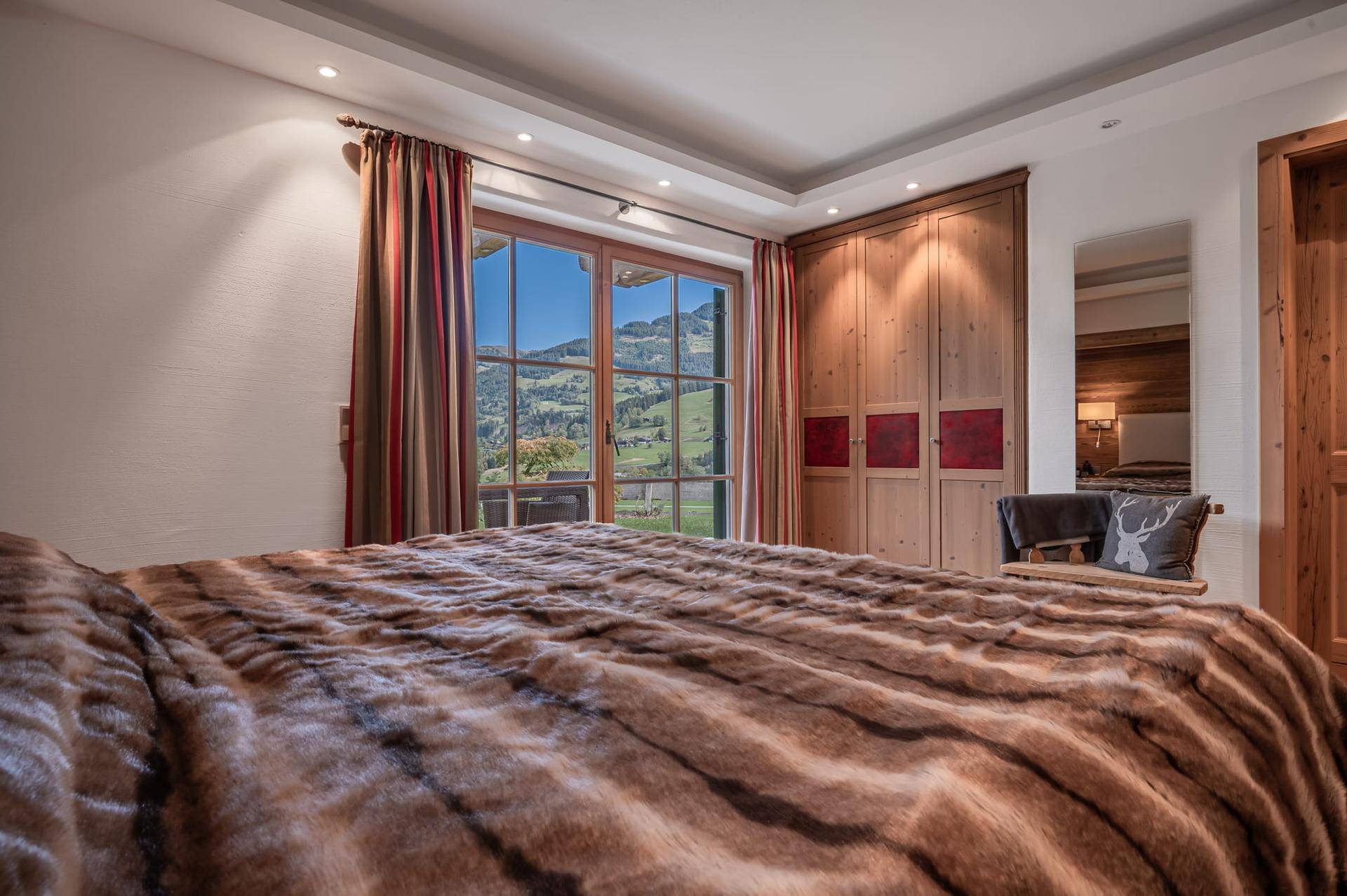 Gemütliches Schlafzimmer mit Holzeinbauschränken und Panoramablick auf die Bergwelt.