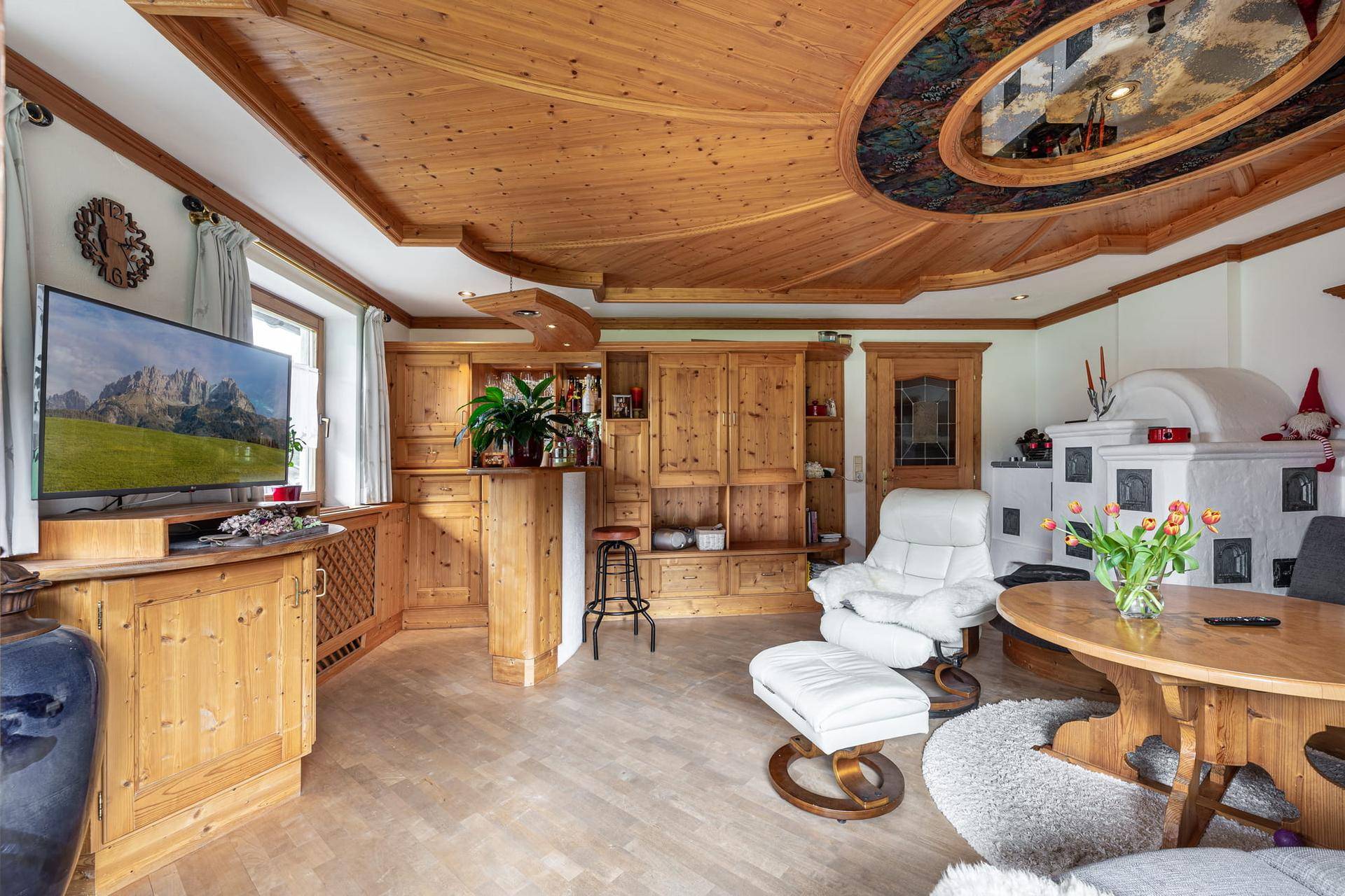 Geräumiges Wohnzimmer mit traditionellem Kachelofen, Holztäfelung und bequemen Sesseln.