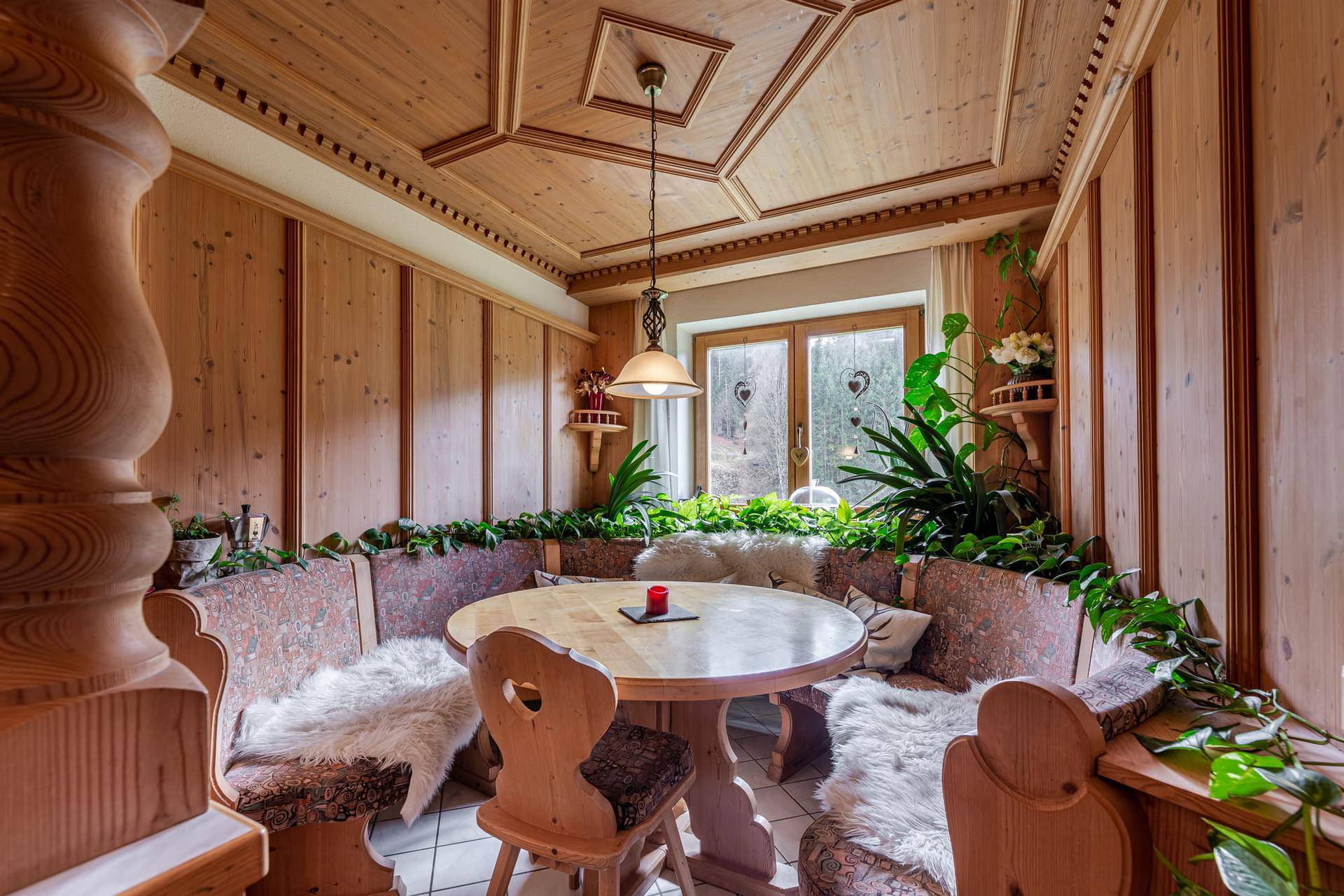 Traditionelle Essecke mit Holztäfelung, Eckbank und Blick in die Natur.