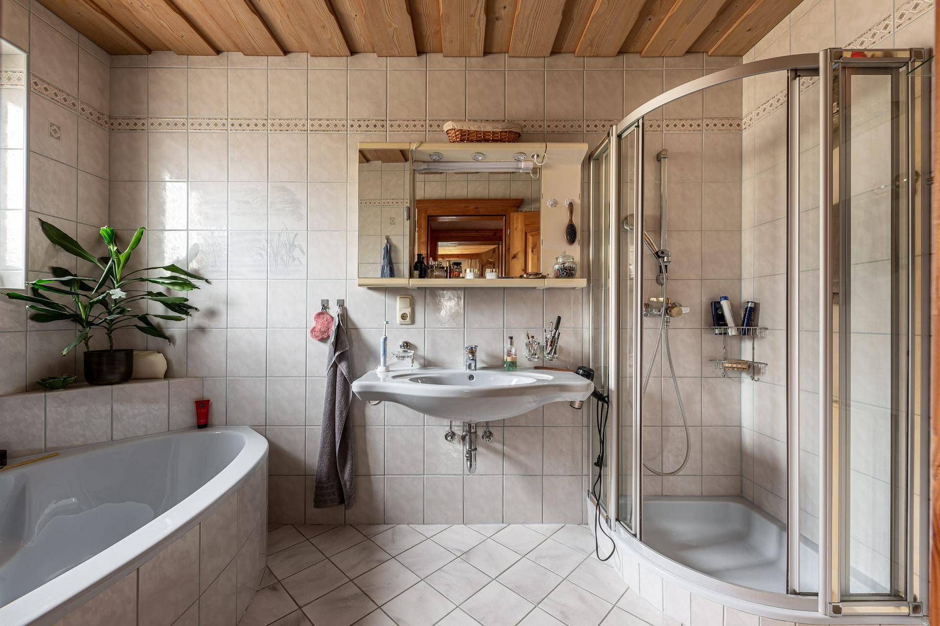Helles Badezimmer mit Badewanne, Dusche und hellen Fliesen.