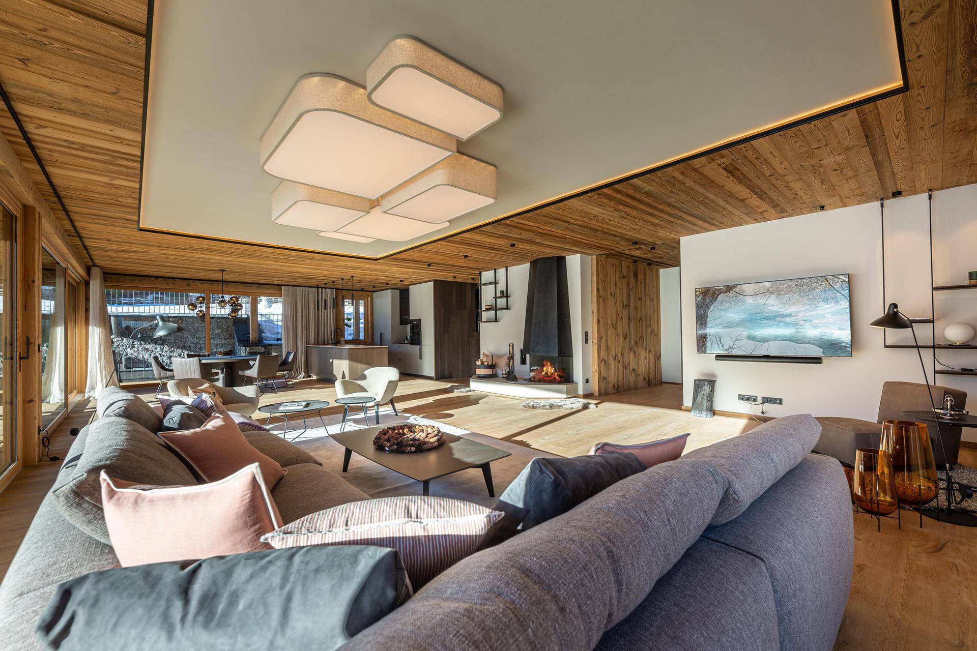 Offener Wohnbereich mit gemütlichem Sofa, Kamin, Fernseher und Blick auf den Essbereich und die Küche.