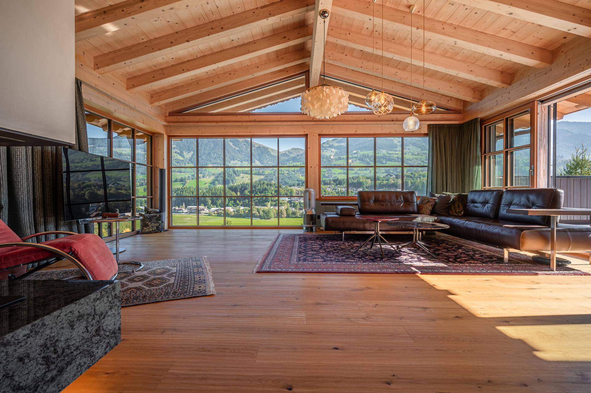 Großzügiges Wohnzimmer mit hohen Holzdecken, Eichenparkett und beeindruckendem Bergblick durch Panoramafenster.