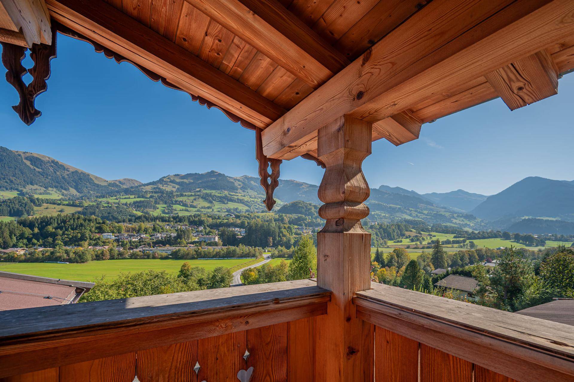 Traditioneller Holzbalkon mit kunstvollen Schnitzereien und weitem Blick über grüne Täler und Berge.