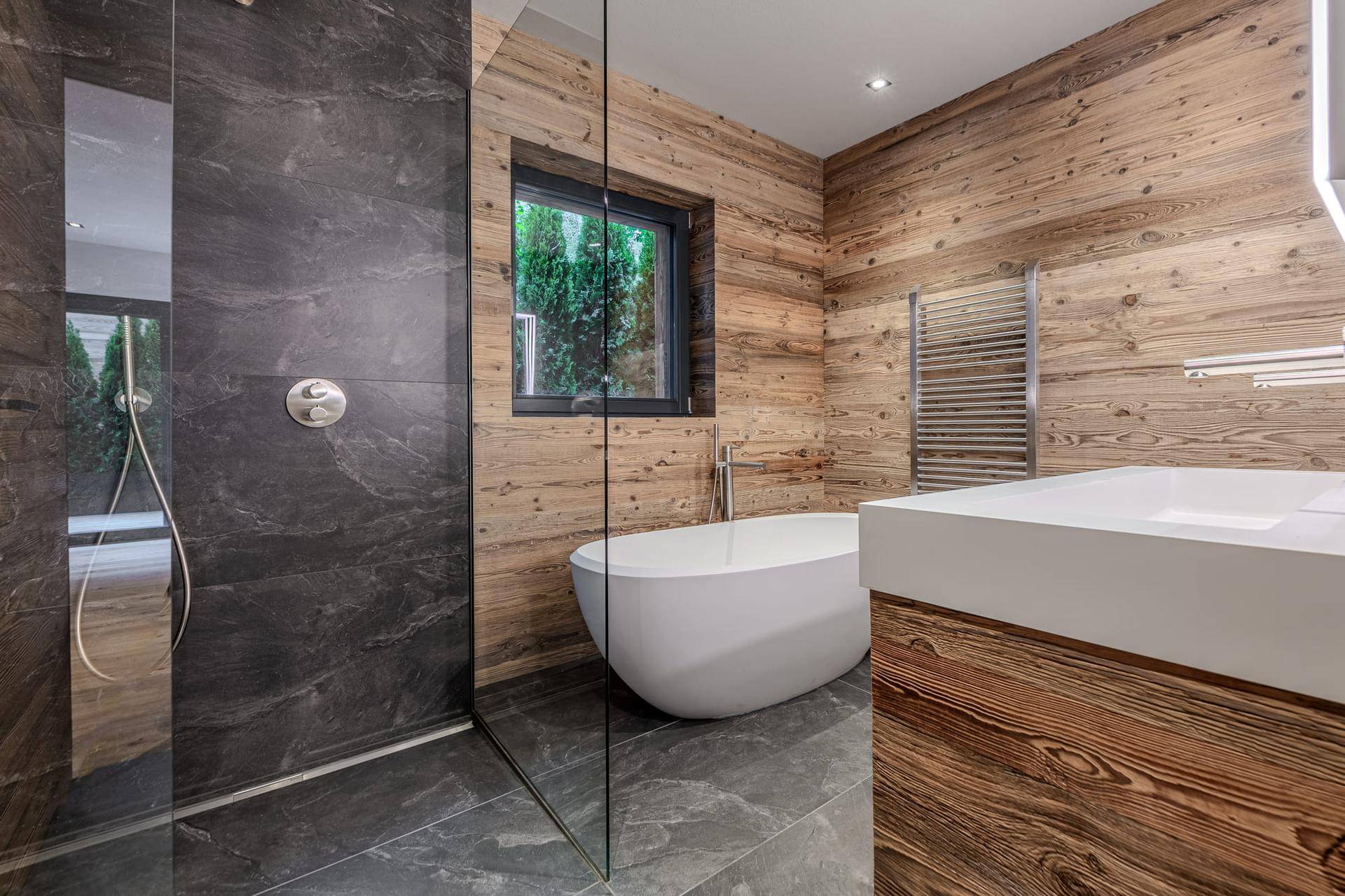 Modernes Badezimmer mit begehbarer Dusche, freistehender Badewanne und Holzelementen.