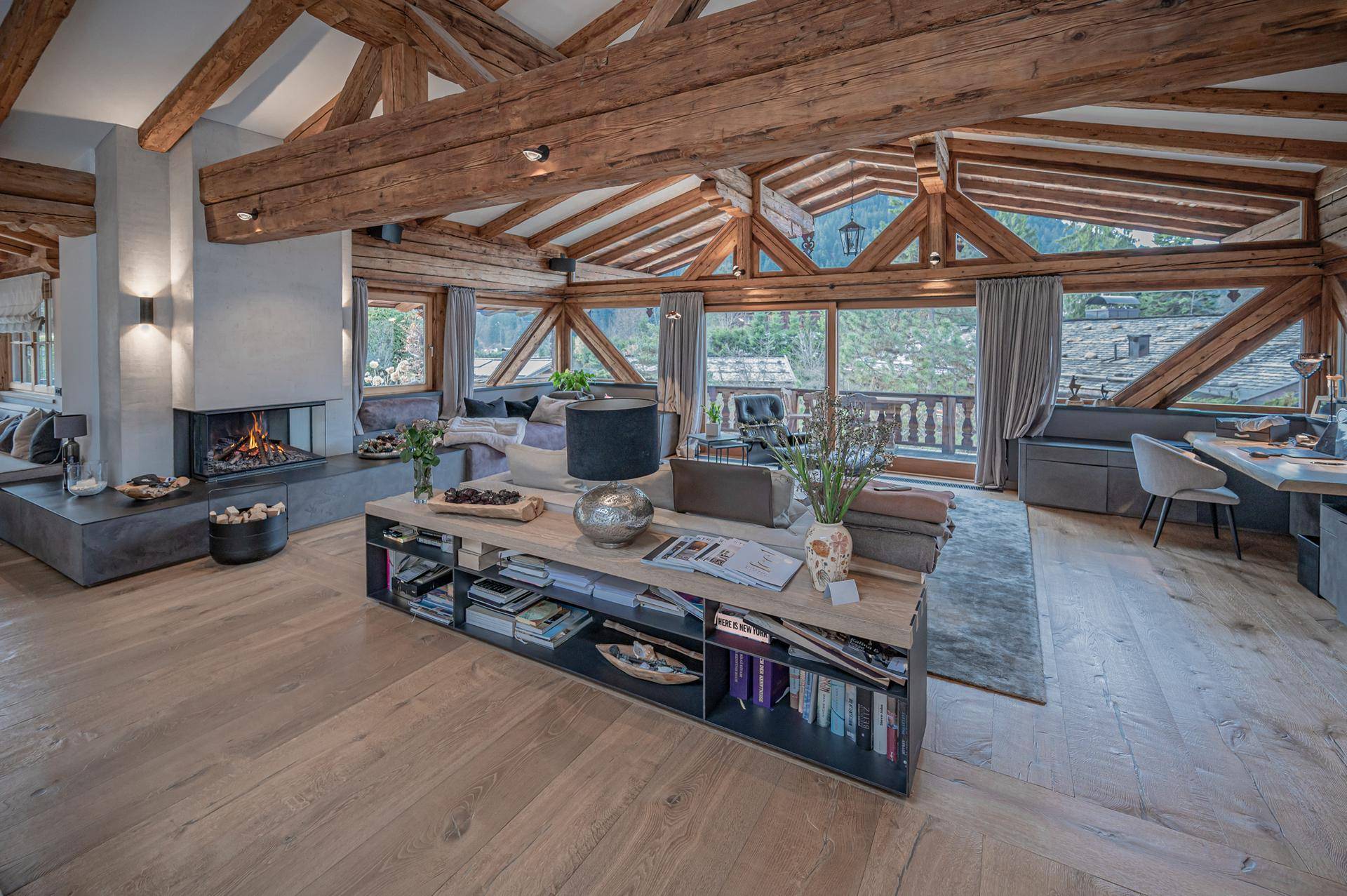 Geräumiges Wohnzimmer mit hohen Decken, freiliegenden Holzbalken und Kamin, bietet einen weiten Ausblick.
