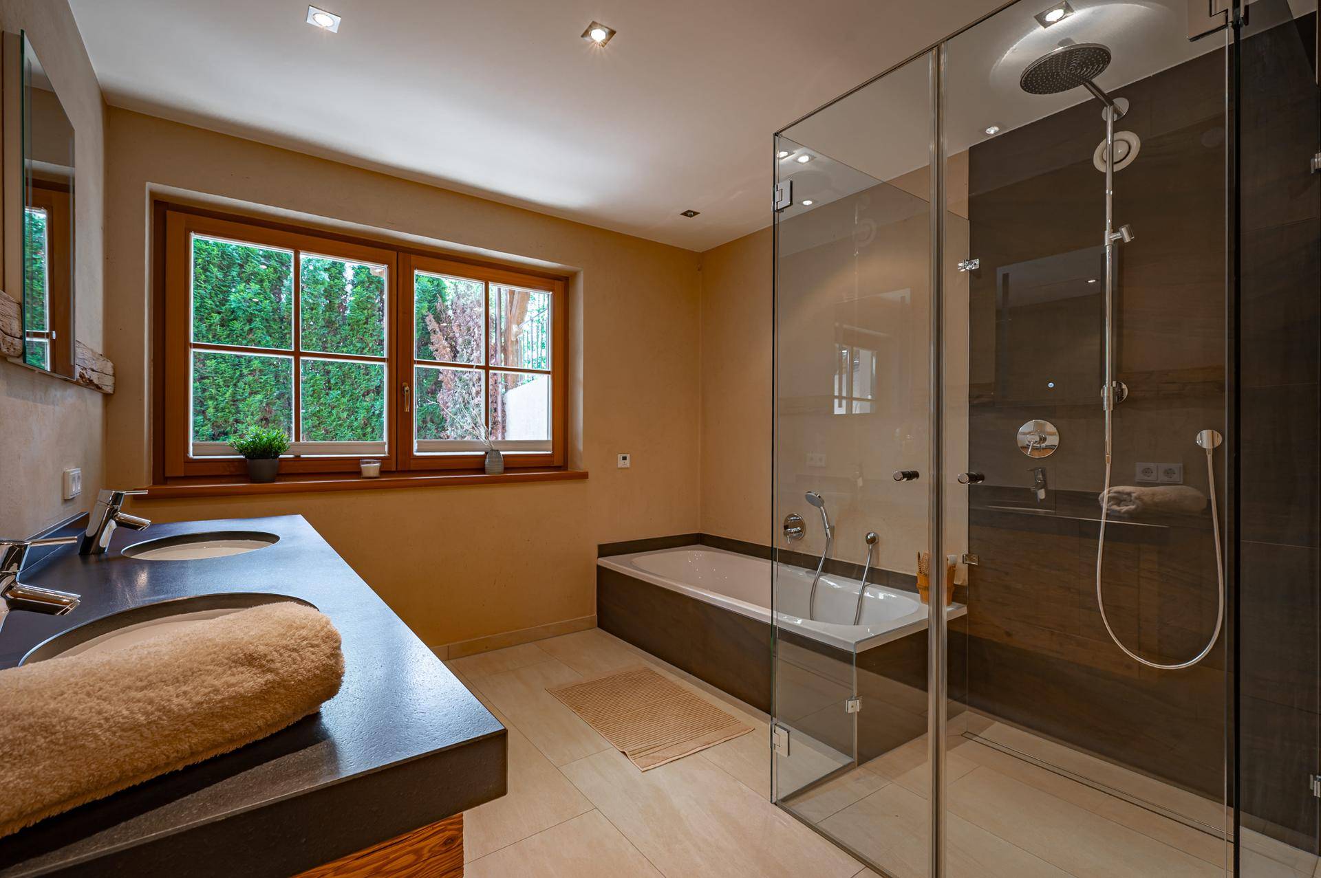 Modernes Badezimmer mit Doppelwaschbecken, Badewanne, großer begehbarer Dusche und Fenster.